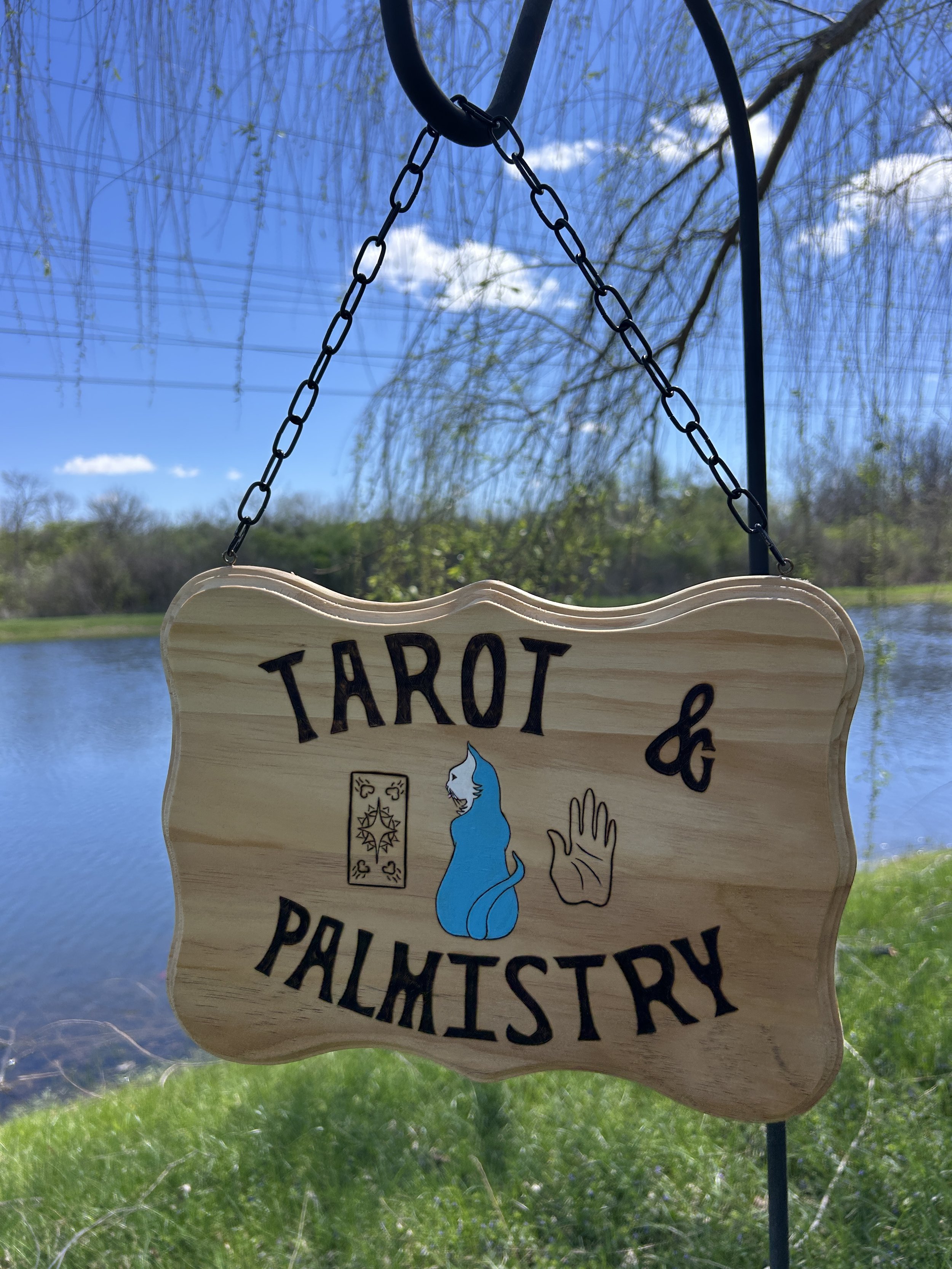 A vintage-inspired sign reads "Tarot & Palmistry" and shows the back of a tarot card, a blue cat, and the palm-side of a hand