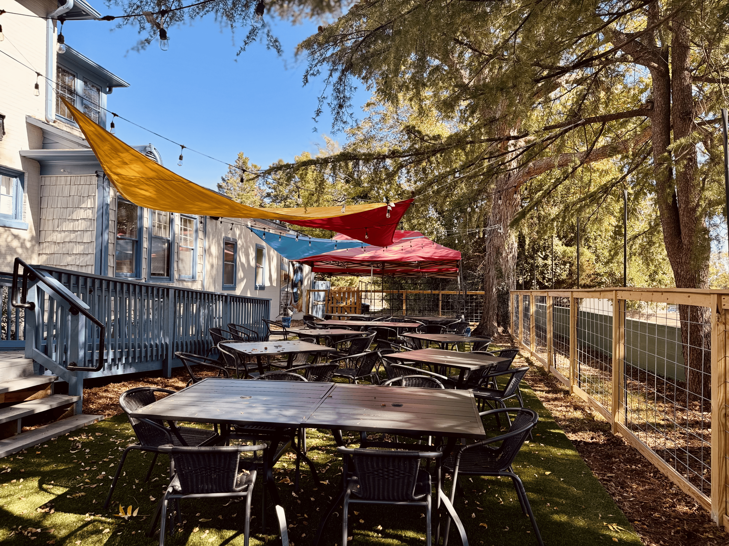 The outdoor event space with an accessibility ramp, sun sails, and plenty of tables and chairs, with a stage for music