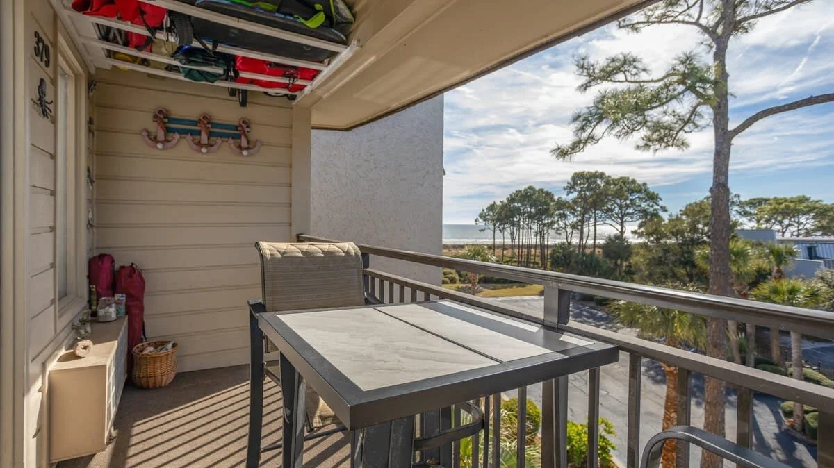 Balcony with table and chair overlooking trees and ocean view