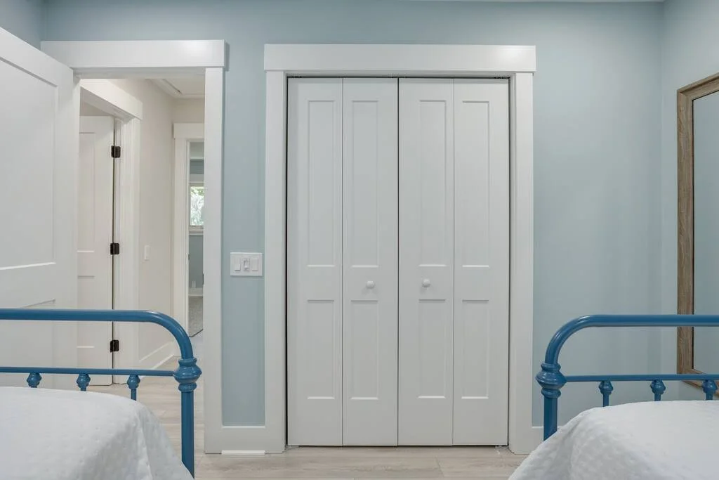 Bedroom with blue bed frames, white closet doors, and light blue walls.
