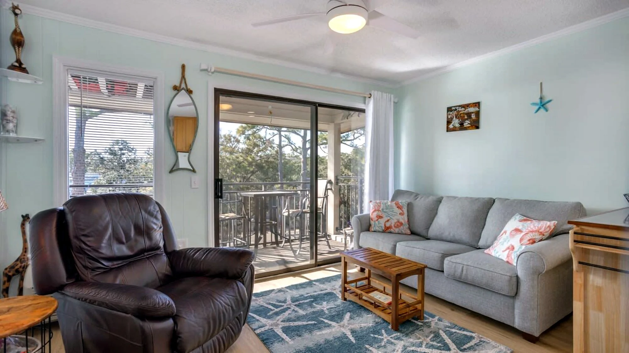 Living room with couch, recliner, blue rug, and sliding glass door to balcony.