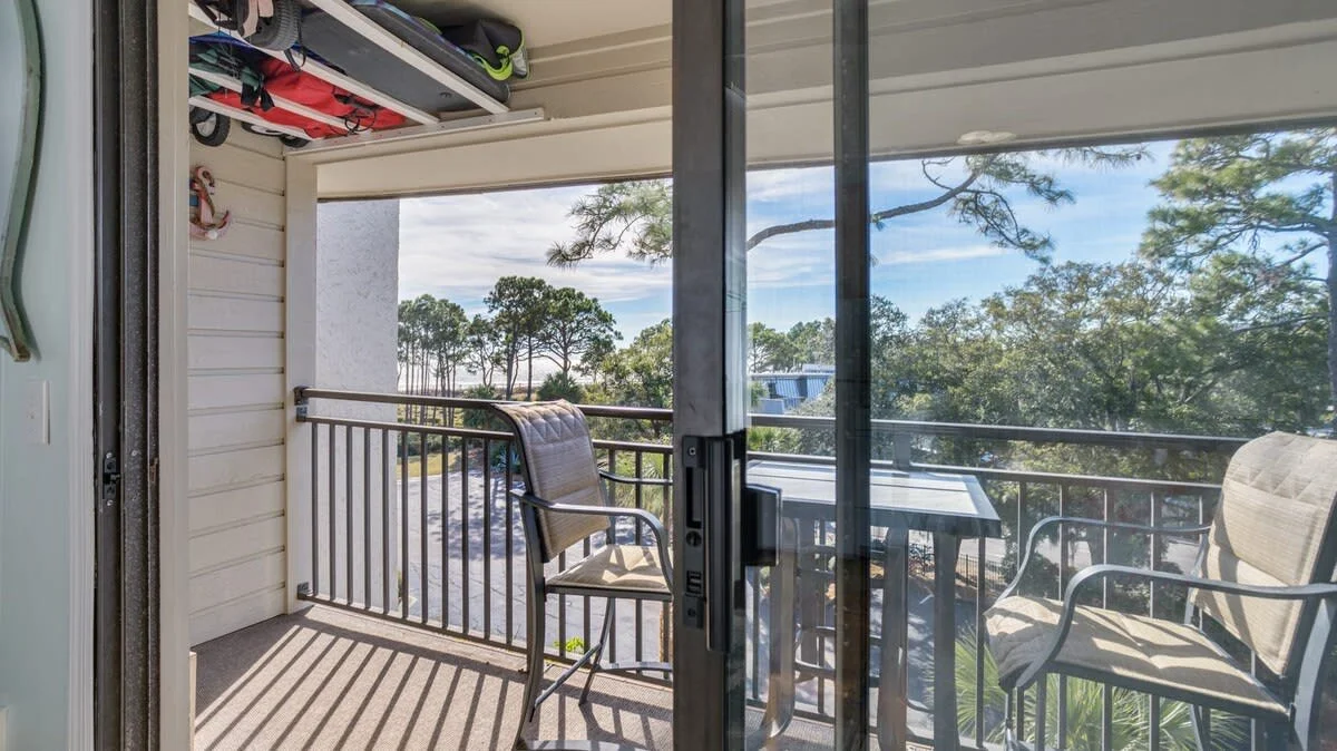 Outdoor balcony with chairs and table overlooking trees and a scenic view.