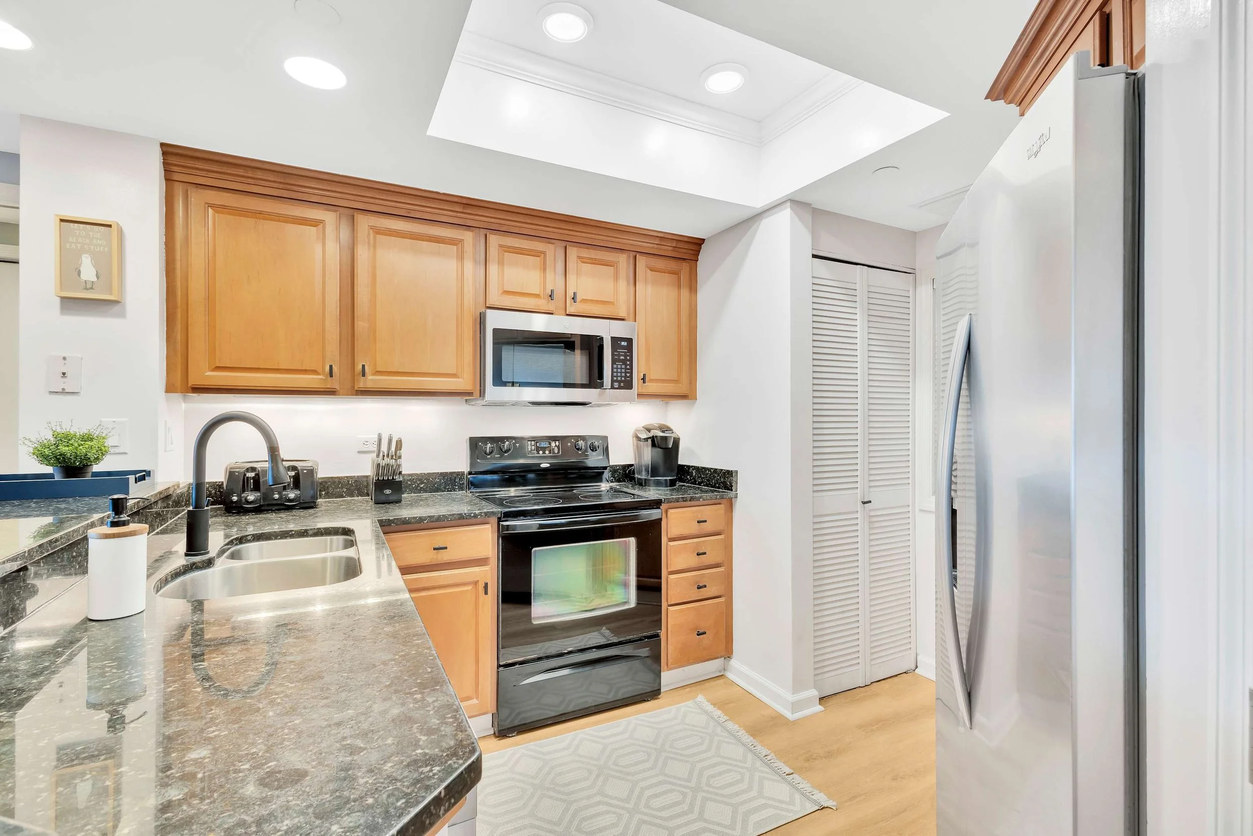 Modern kitchen with wooden cabinets, stainless steel appliances, and granite countertops.