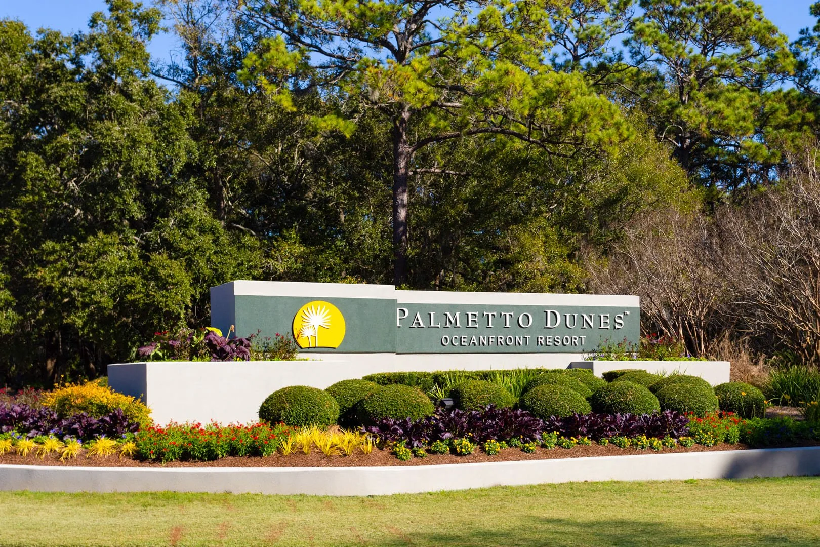 Entrance sign for Palmetto Dunes Oceanfront Resort surrounded by landscaped greenery and colorful flowers.