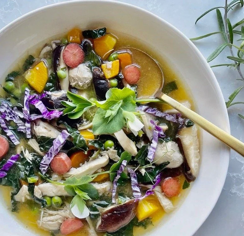 Colorful nourishing chicken and vegetable soup with herbs, squash, greens, and olive oil for a menopause cooking class.