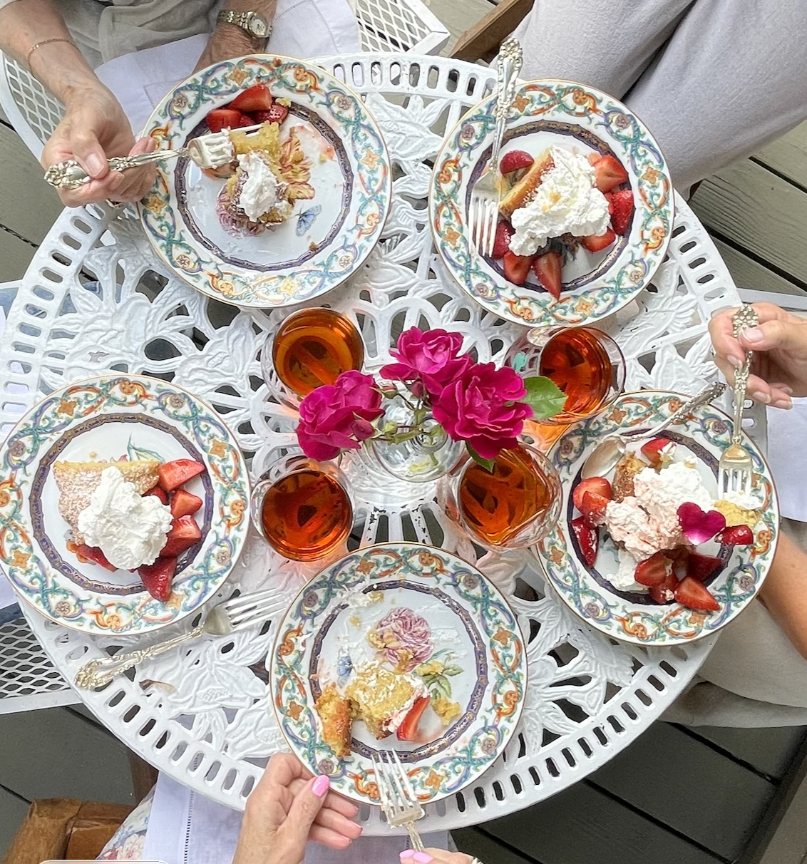 Women gathered around a table sharing strawberry almond cake and tea.