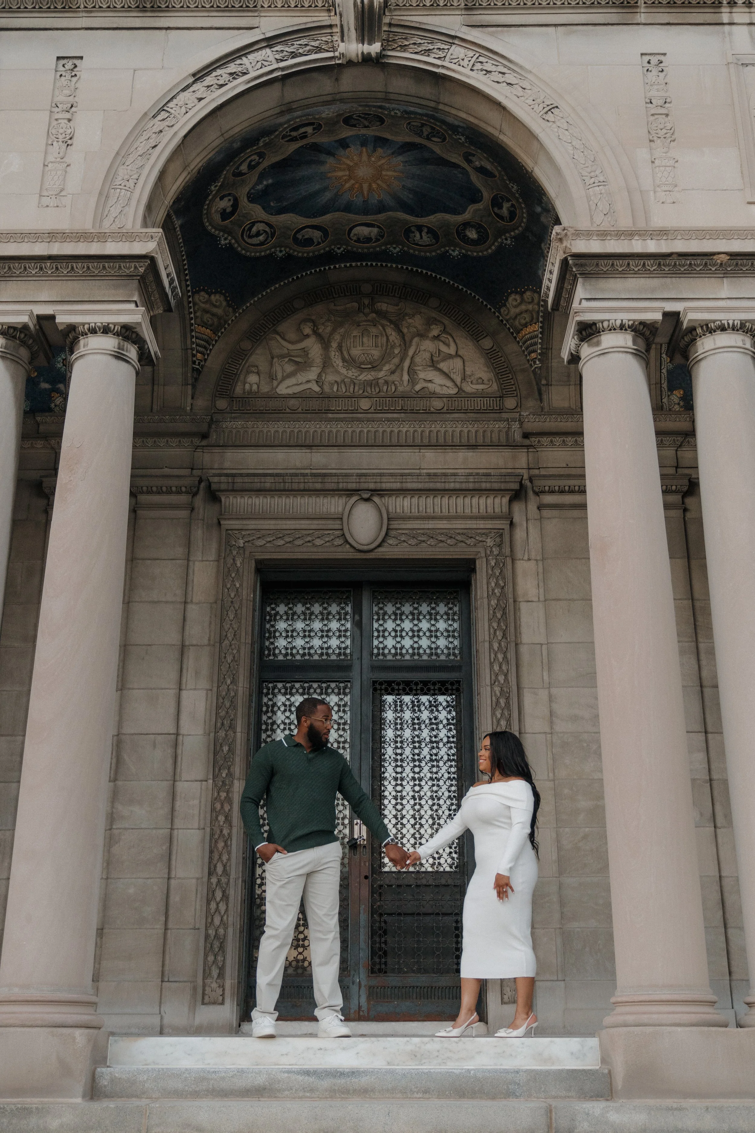 Couple holding hands in front of historic architecture during a downtown Sarasota engagement session.