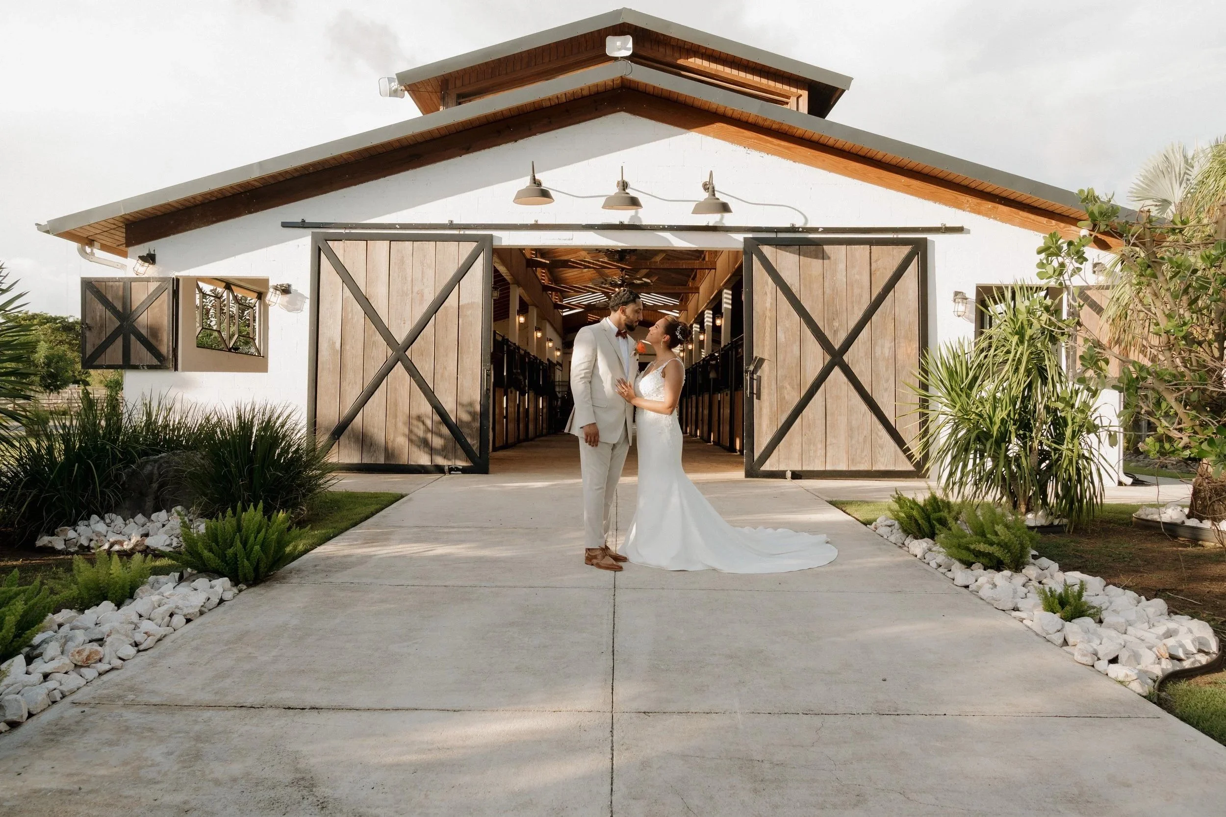 Bride and groom standing outside a modern barn wedding venue photographed by Sarasota wedding photographer Evelize Rivera.