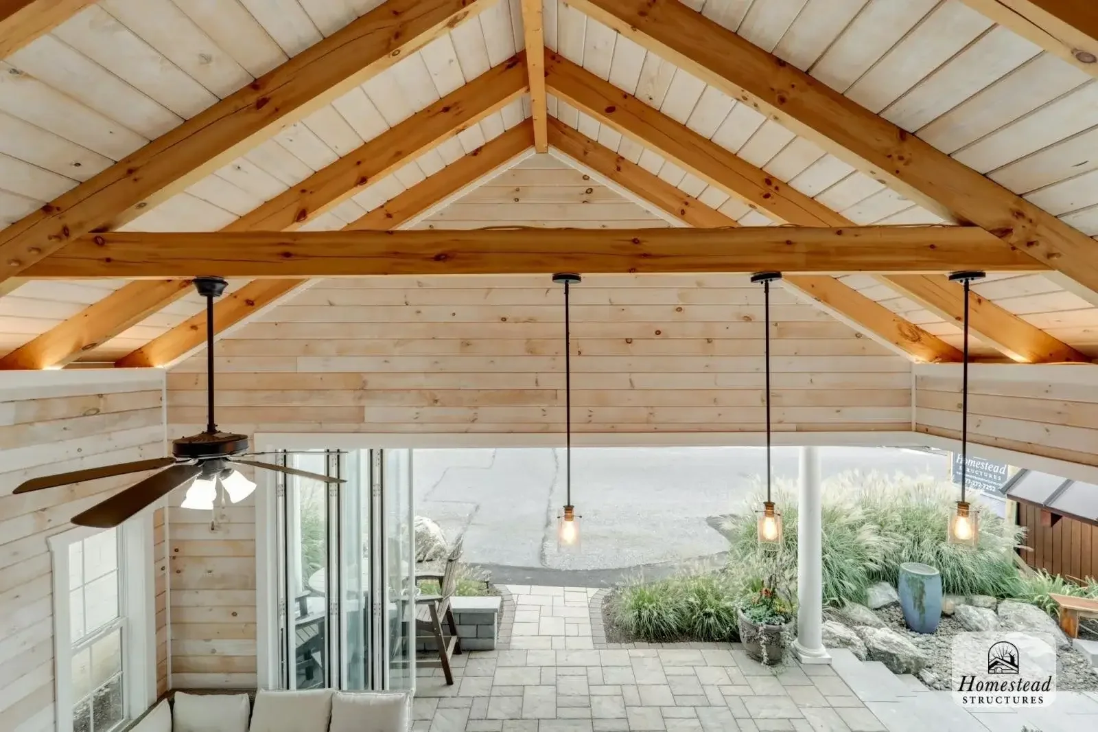 Loft area with a red bed, black metal railing, and wood-paneled walls and ceiling in a rustic home.