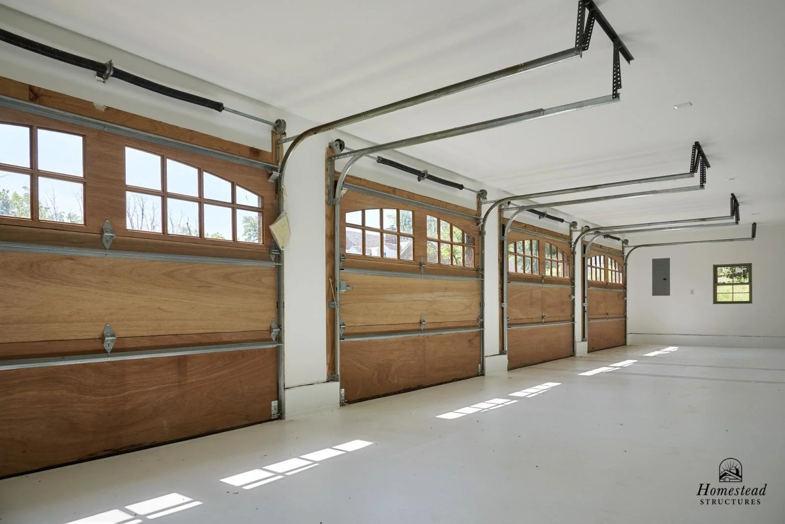 A spacious garage with four wooden paneled garage doors with small windows at the top, partially open.