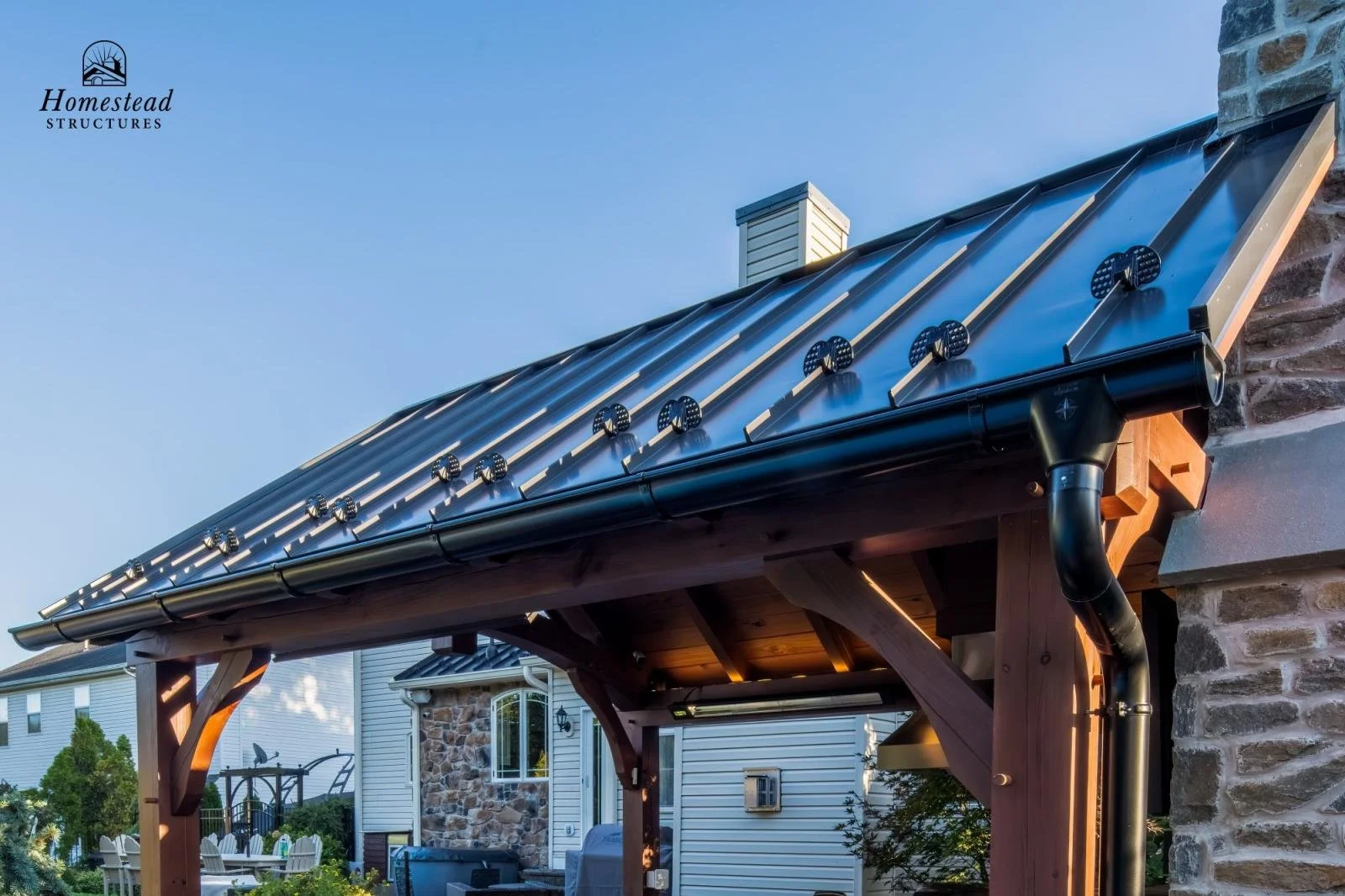 Close-up of a metal roof with solar panels and a black gutter on a suburban house.