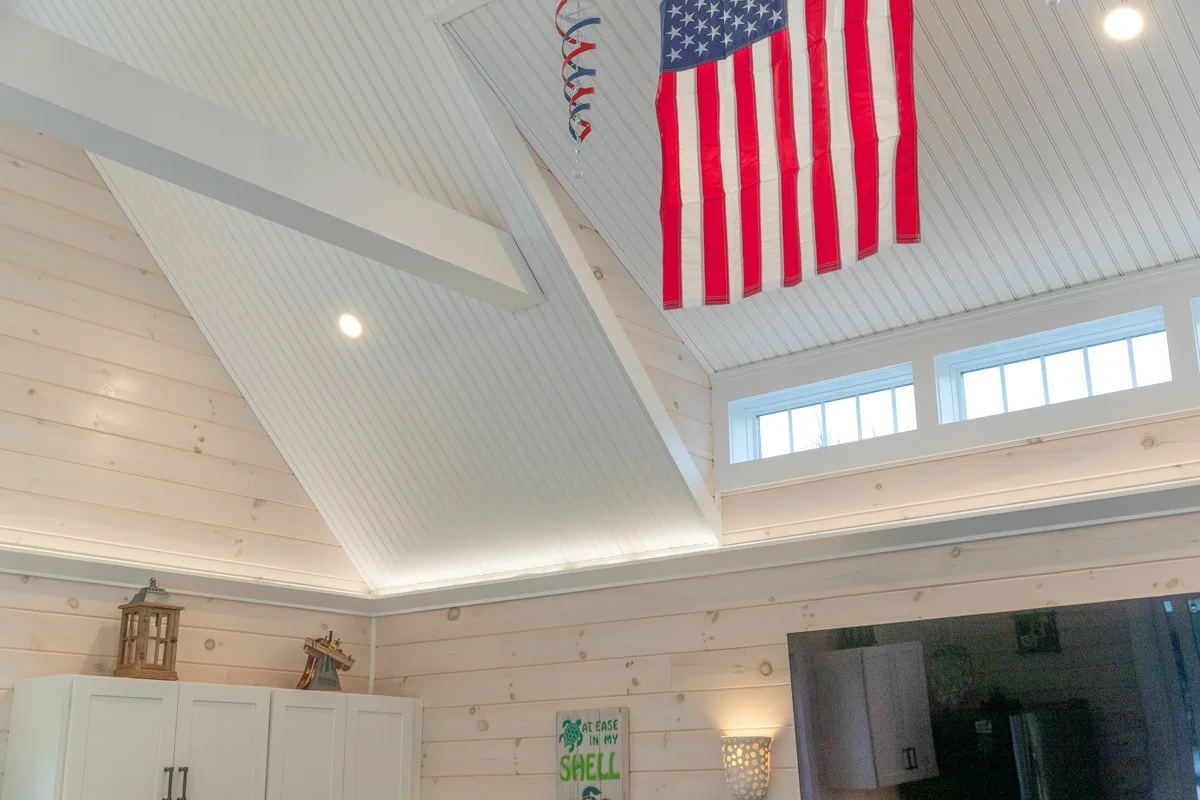 American flag hanging inside a room with white wooden walls and a vaulted ceiling.