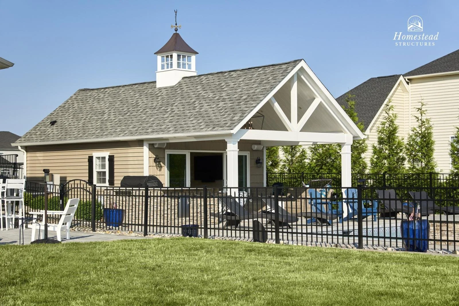 Backyard with a house featuring a porch, yard, patio furniture, and a black metal fence