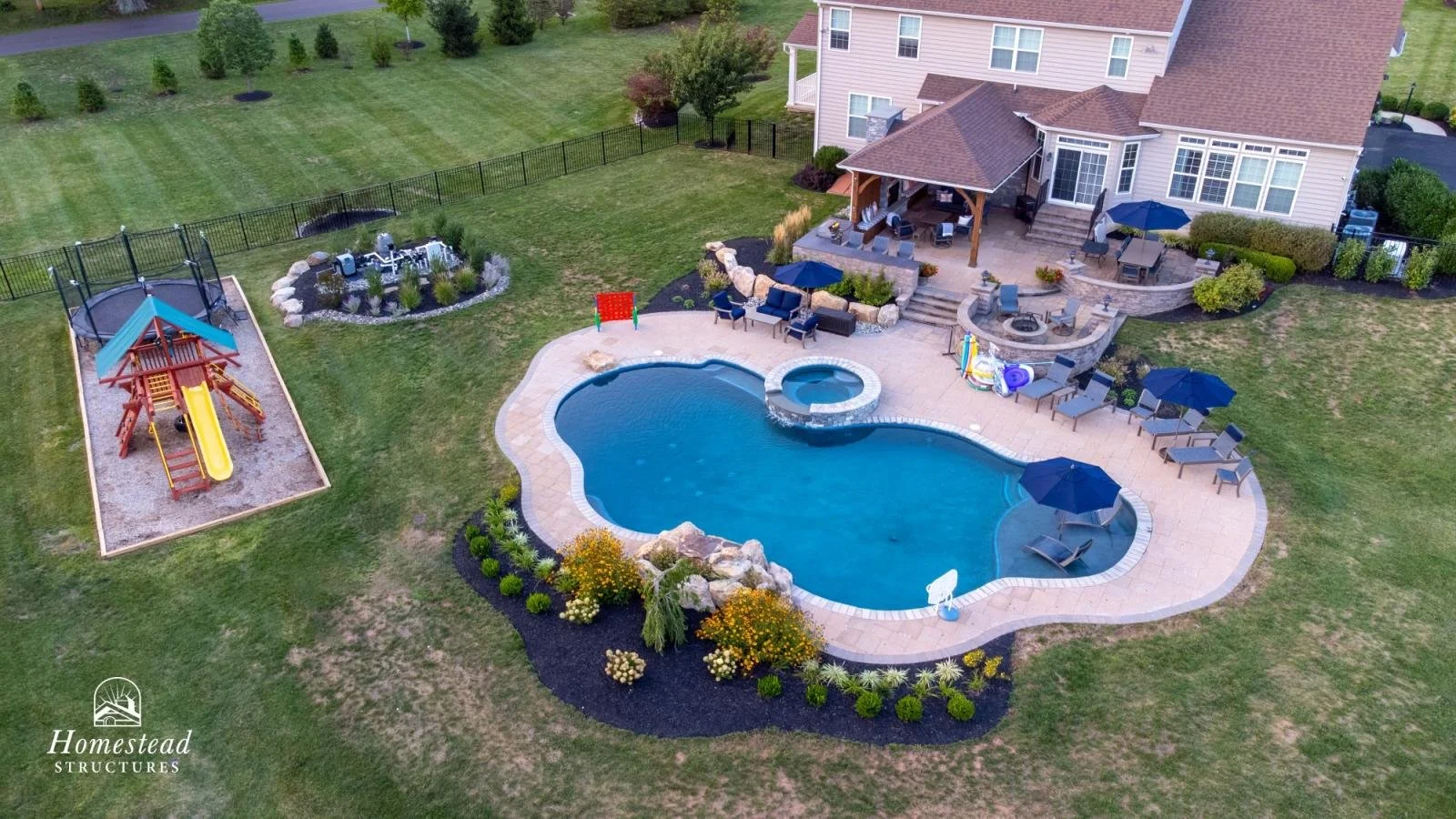 A backyard with a swimming pool, hot tub, covered patio with outdoor furniture, children's play area with a slide, and a garden area with shrubs and flowers.