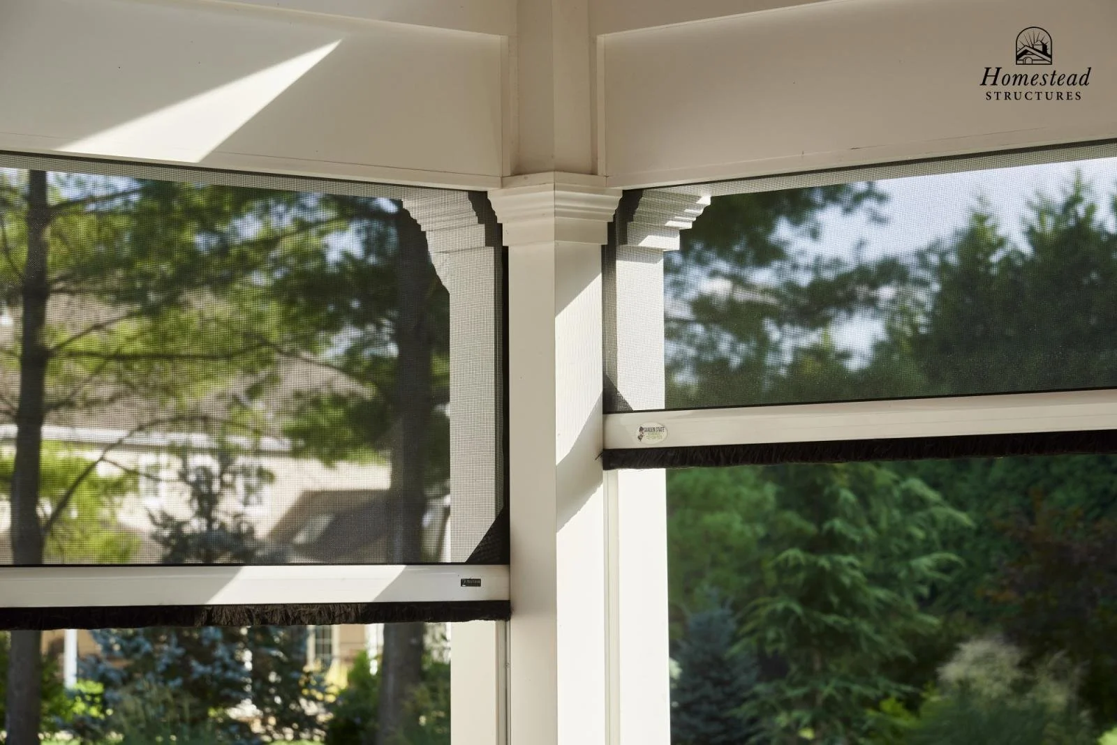 View of window screens and corner structure of a screened porch with trees and sky visible outside.