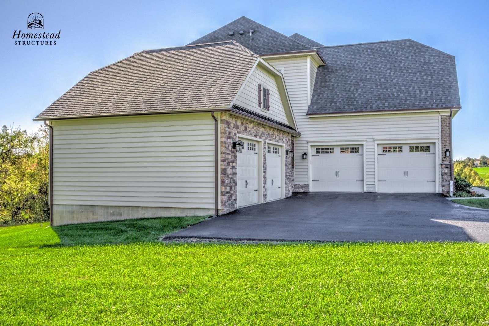 Front view of a modern house with a well-maintained lawn, three-car garage, and a combination of brick and siding exterior.
