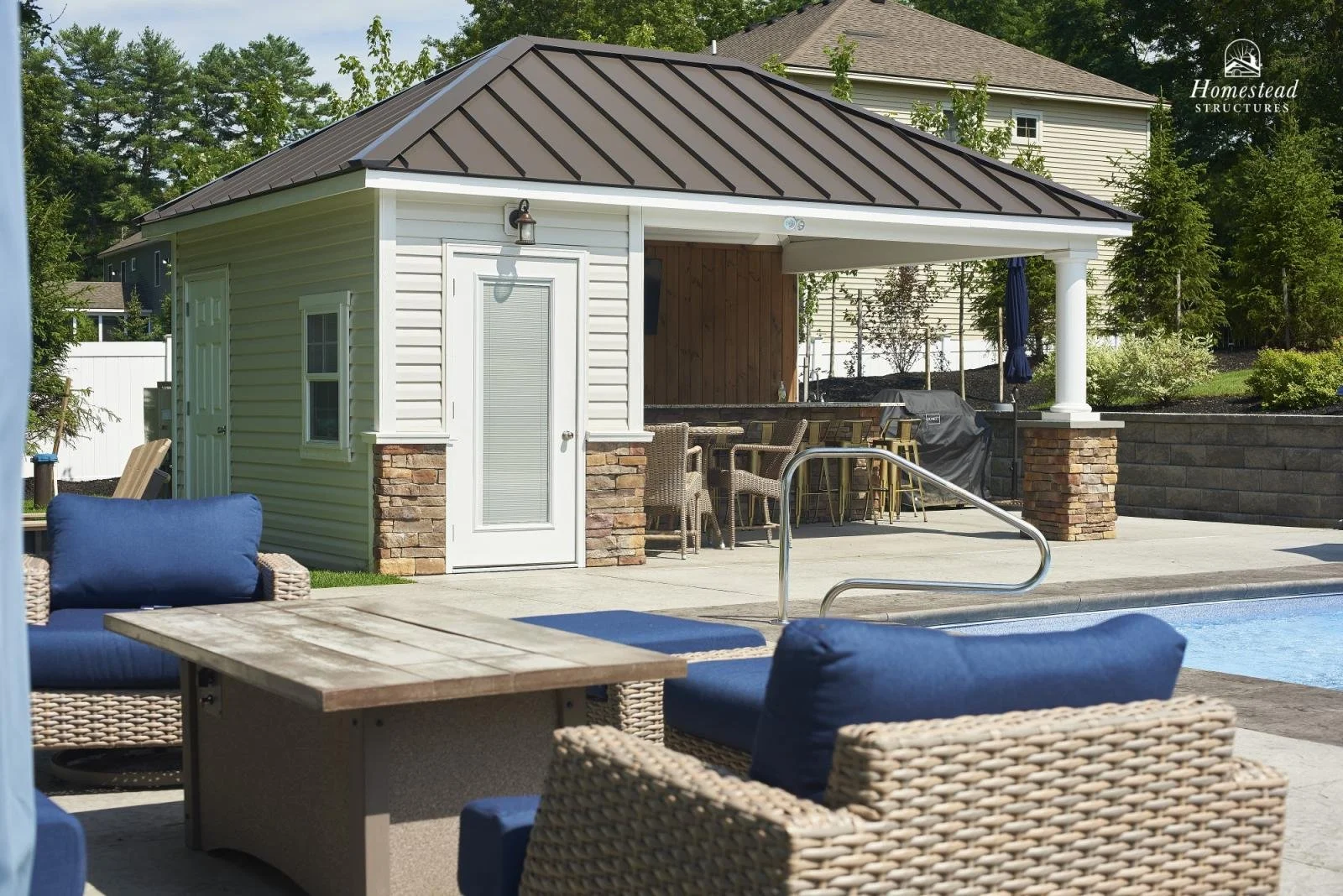 Backyard with a pool, outdoor furniture, a small building with a metal roof, and surrounding greenery.