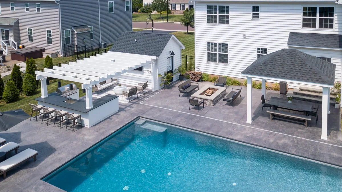 Backyard with swimming pool, outdoor seating areas, a fire pit, and a house with white siding