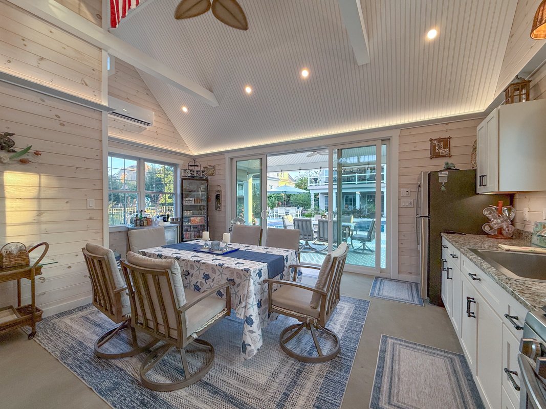 Kitchen and dining area with a wooden table, six chairs, a sliding glass door leading to an outdoor patio with a pool, and kitchen cabinets with a granite countertop.