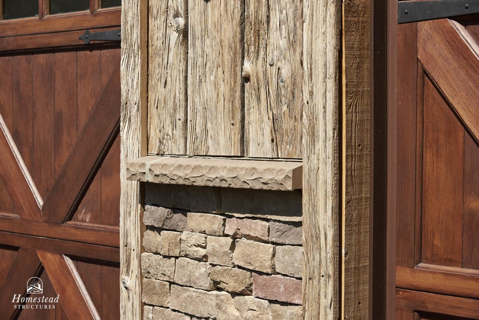 Close-up of a rustic outdoor fireplace with wooden planks and brickwork, surrounded by wooden fence panels.