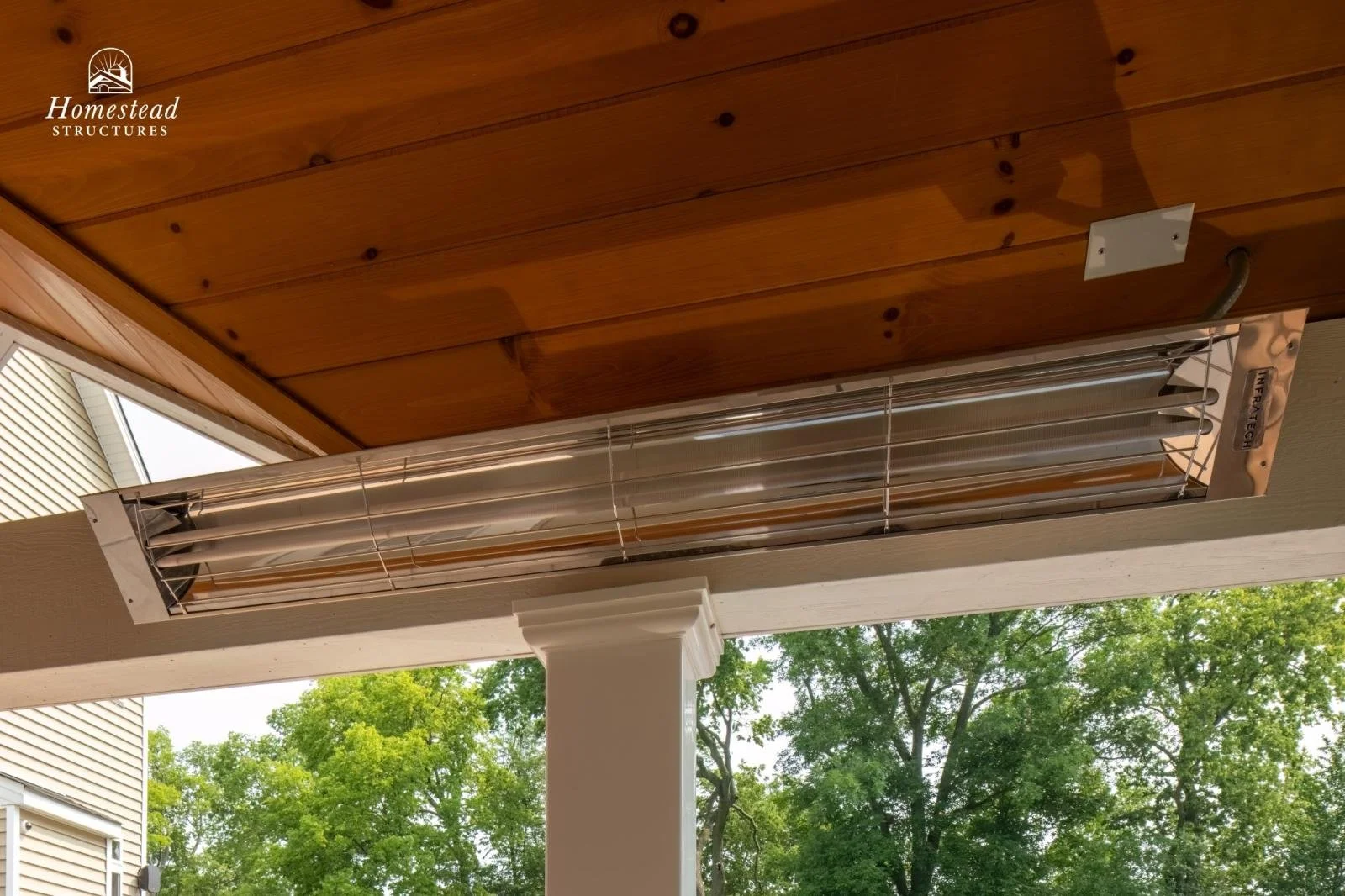 Outdoor heating unit mounted on a wooden porch ceiling, with trees visible in the background.
