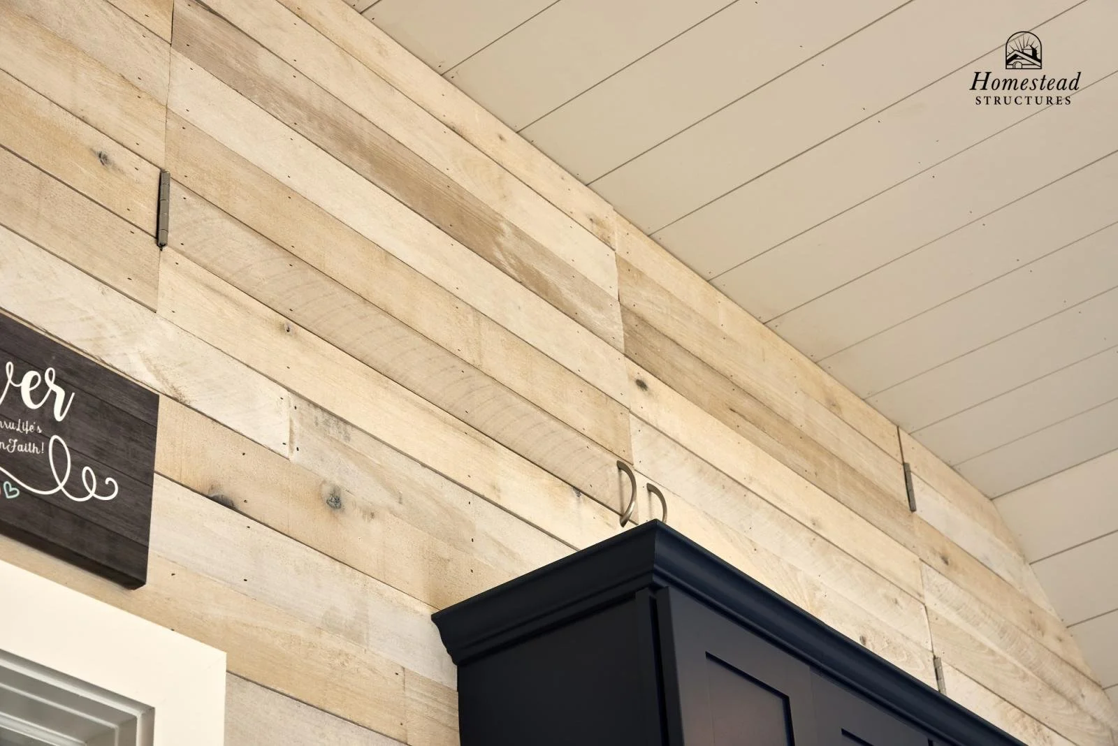 Close-up of a wooden wall with a black cabinet and a small sign with white text in a home interior.