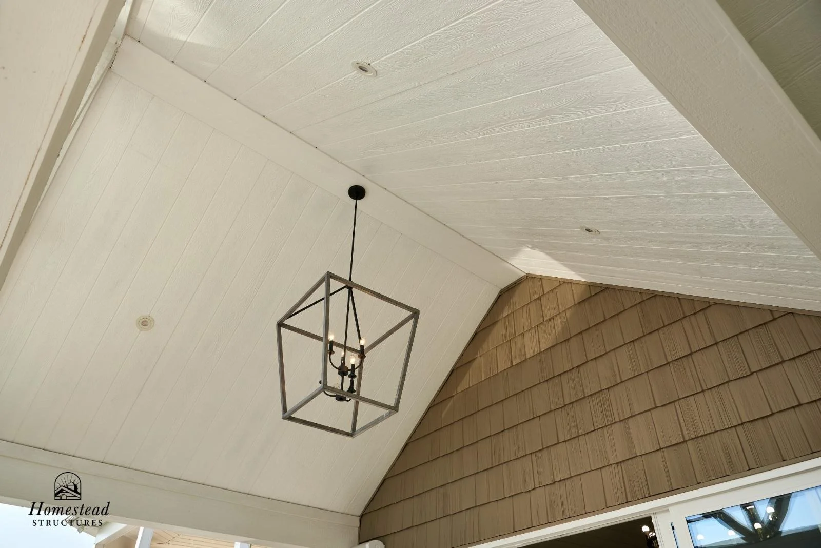 Close-up of a vaulted ceiling with a modern chandelier, combining white and brown wooden panels.