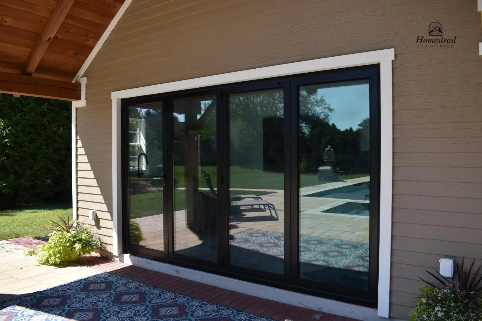 Sliding glass door leading to backyard with patio, outdoor furniture, swimming pool, and green lawn.