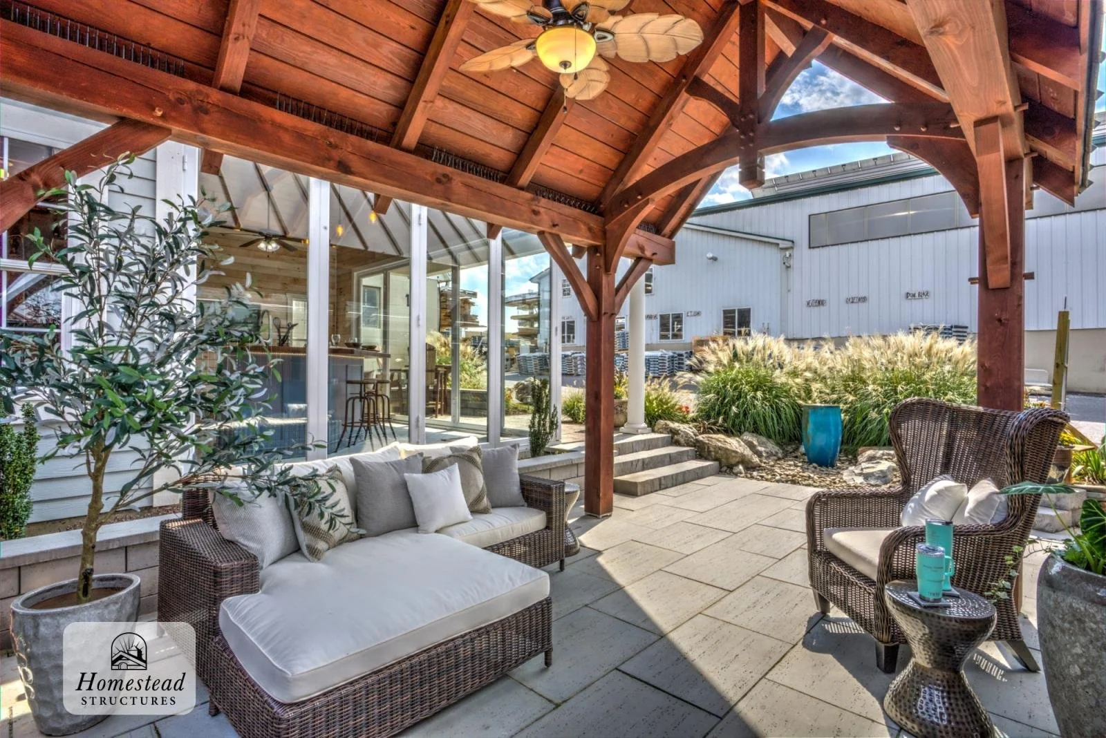Outdoor patio with wicker furniture, potted plants, and a wooden pergola under a sunny sky