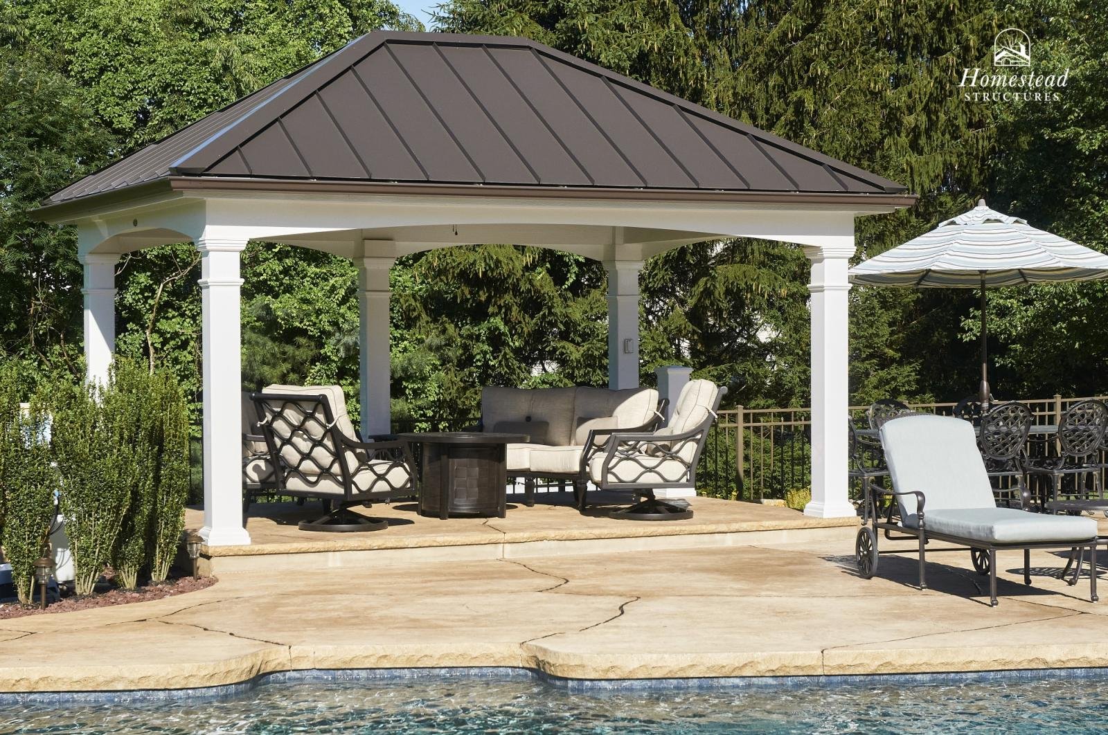 A backyard patio with a gazebo, outdoor furniture, and a swimming pool in the foreground.