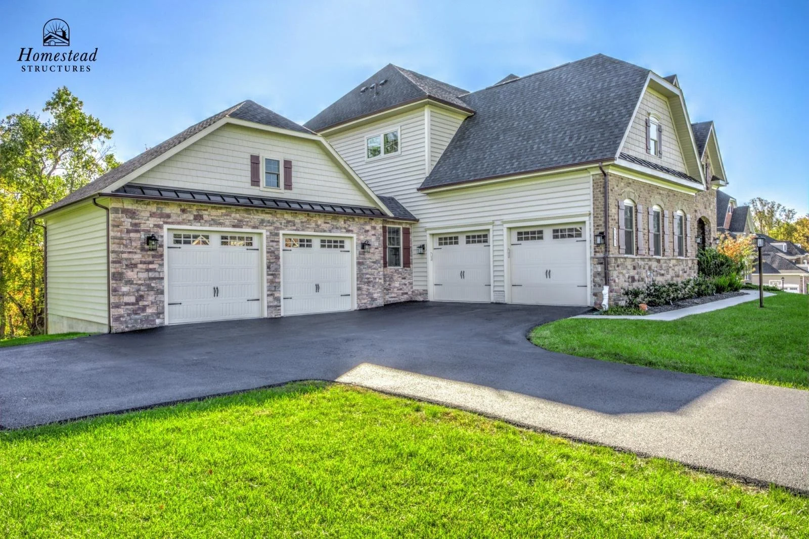 Modern house with a three-car garage, brick and siding exterior, and a well-maintained lawn, under a clear blue sky.