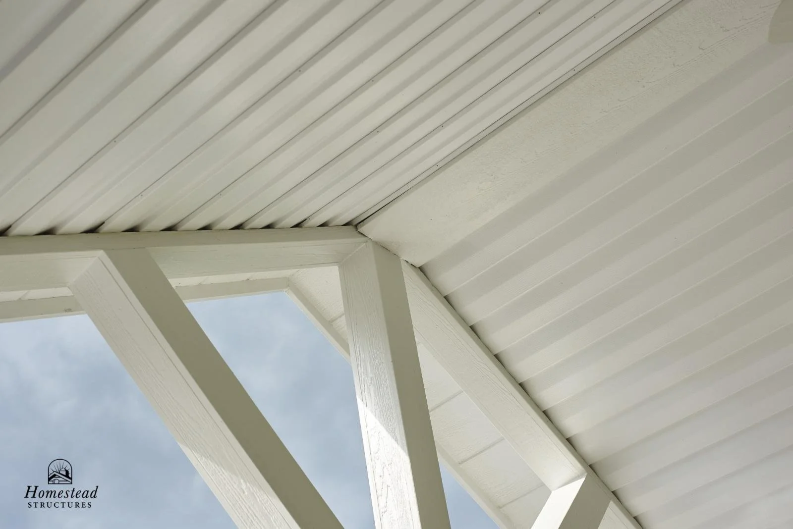 Close-up of a white wooden roof structure with a clear sky visible through an opening.