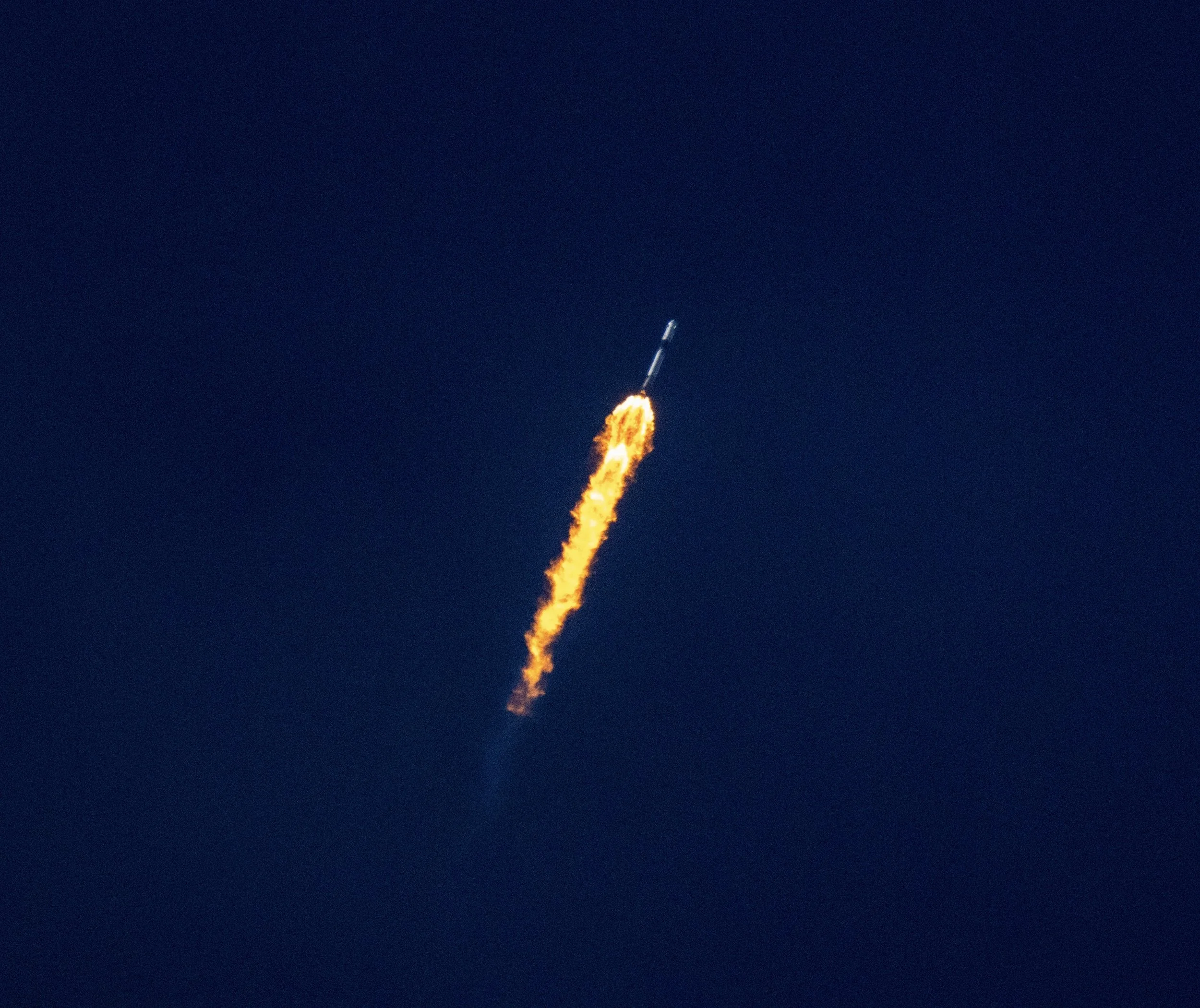 A rocket launching into the night sky with bright flames and smoke trailing behind.