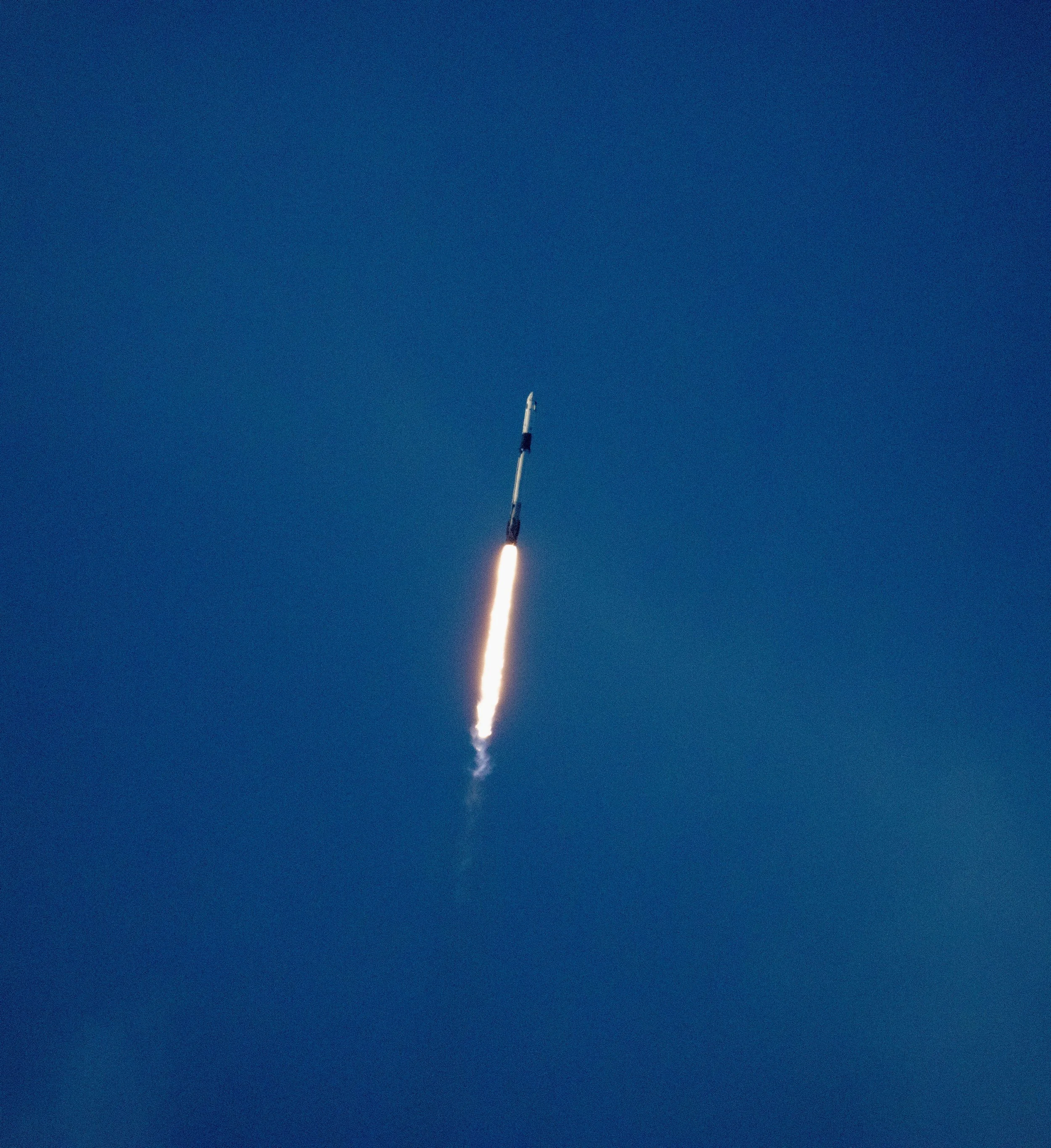 A rocket ascending into the sky with a bright flame and trail of smoke.