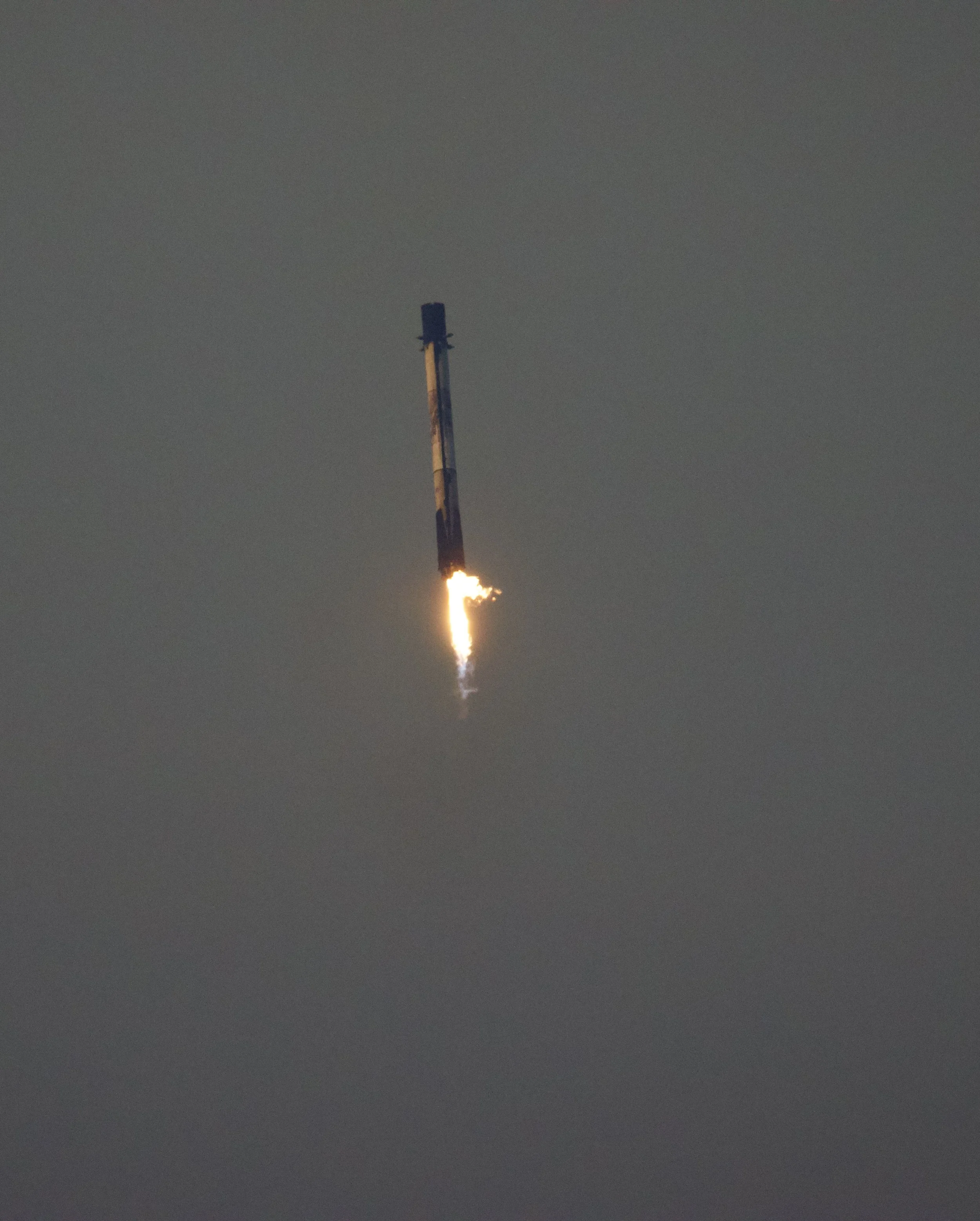 Rocket falling back to the earth with flames at the bottom in a cloudy sky.