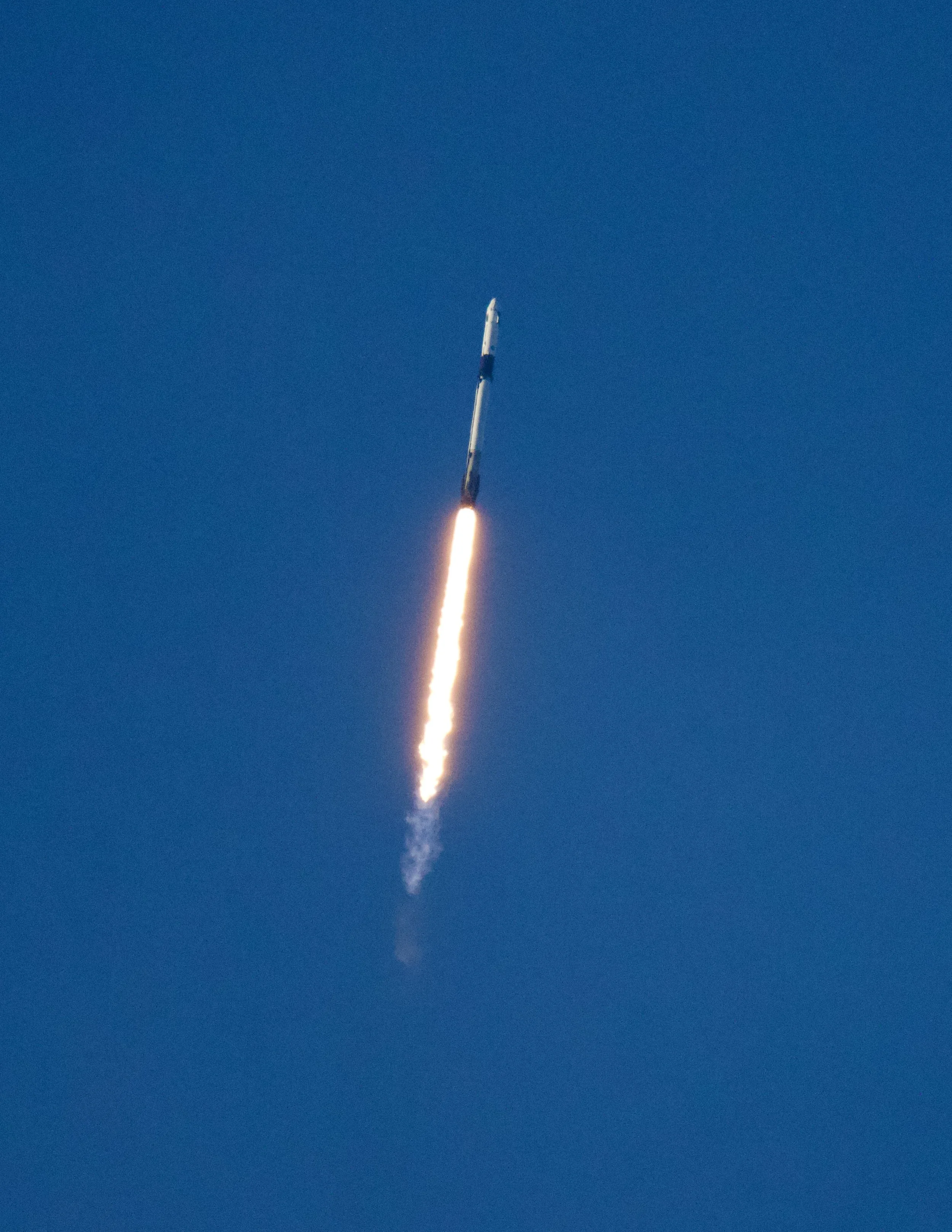 A rocket launching into the blue sky with a fiery trail of exhaust.