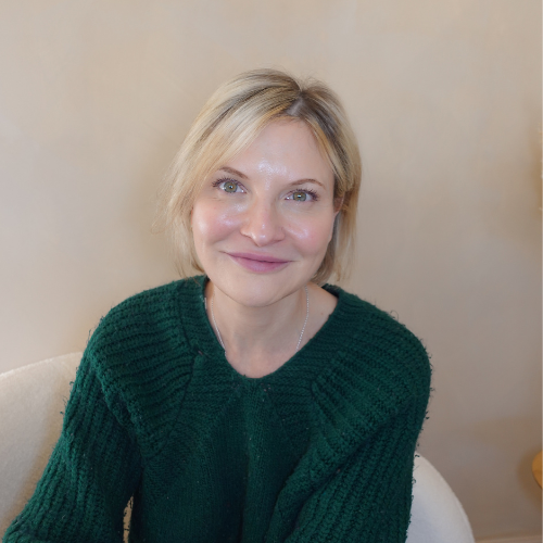 Man with curly hair and glasses, wearing a dark sweater, looking away.