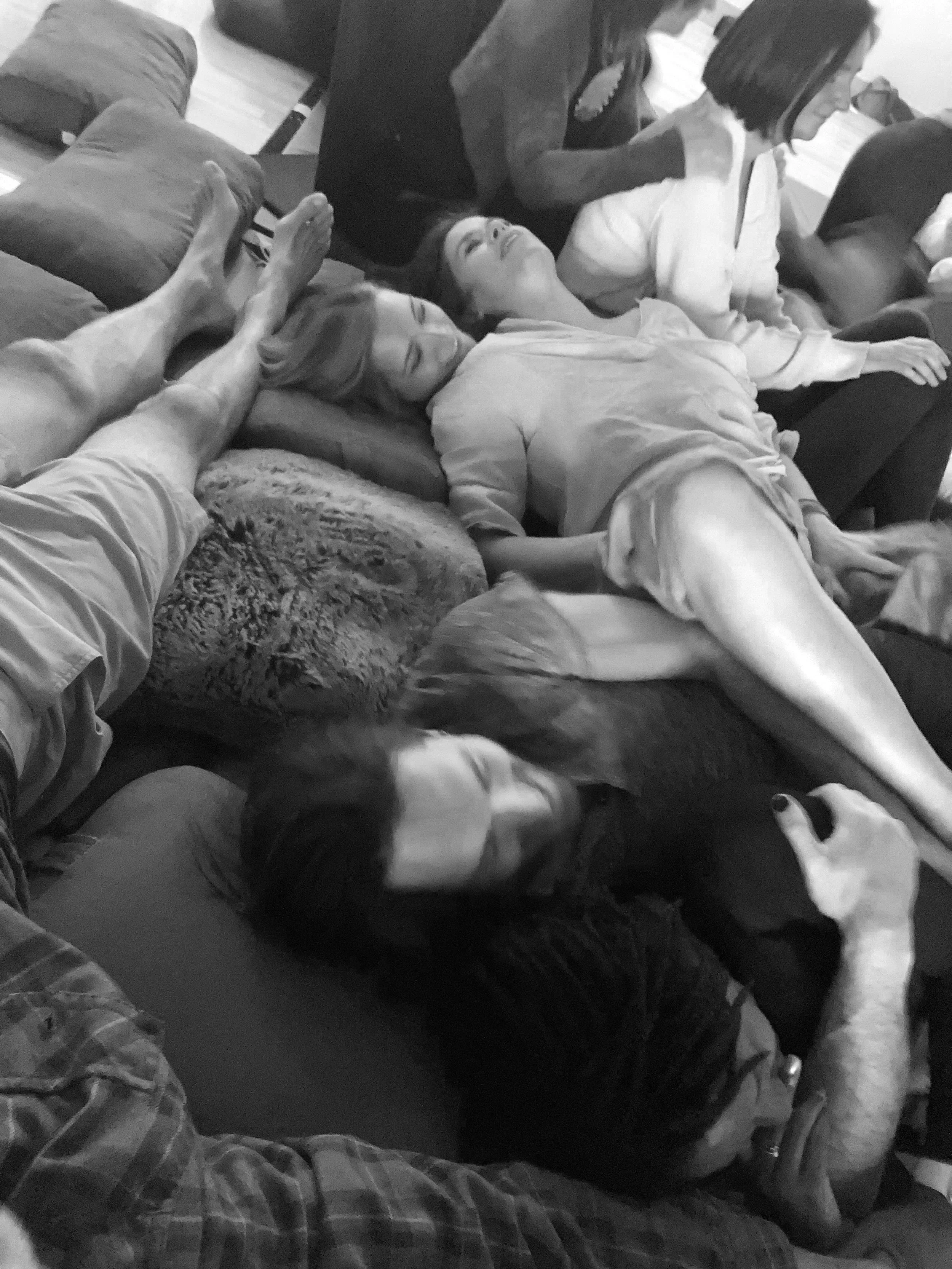 Group of people sleeping and relaxing on couches and beds in a cozy indoor setting.