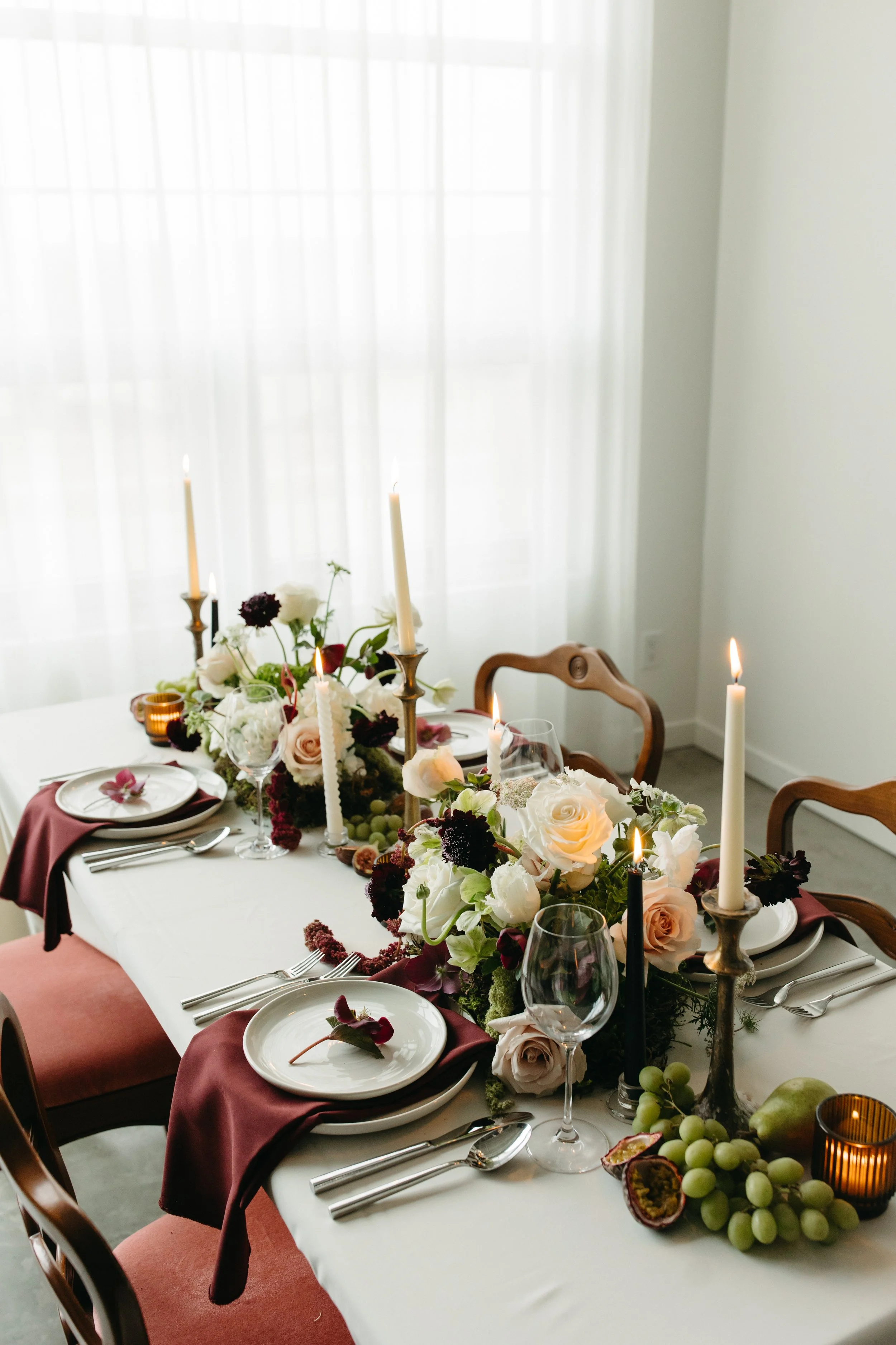 Burgundy and chartreuse wedding reception tablescape with floral centerpieces, fruit, and candles for a wedding done by Petals & Loam Calgary wedding florist.