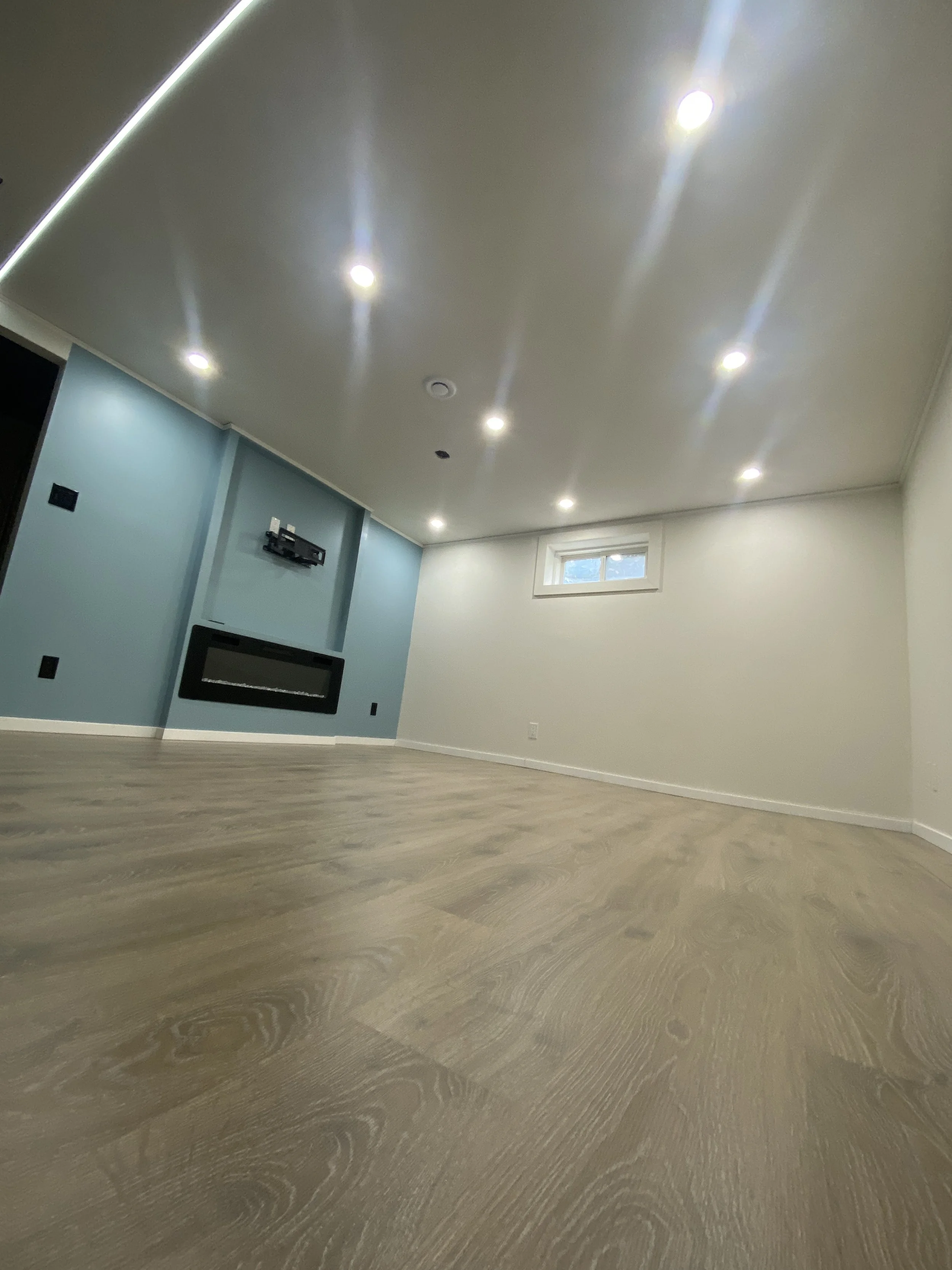 Completed basement renovation with pot lights and LED light track for a modern finish.