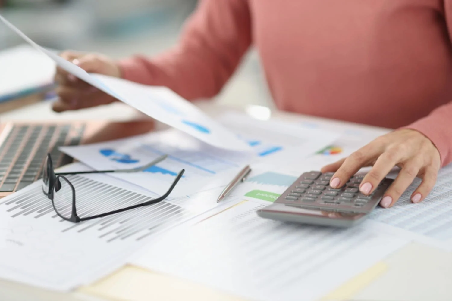 A person using a calculator while reviewing credit report documents.