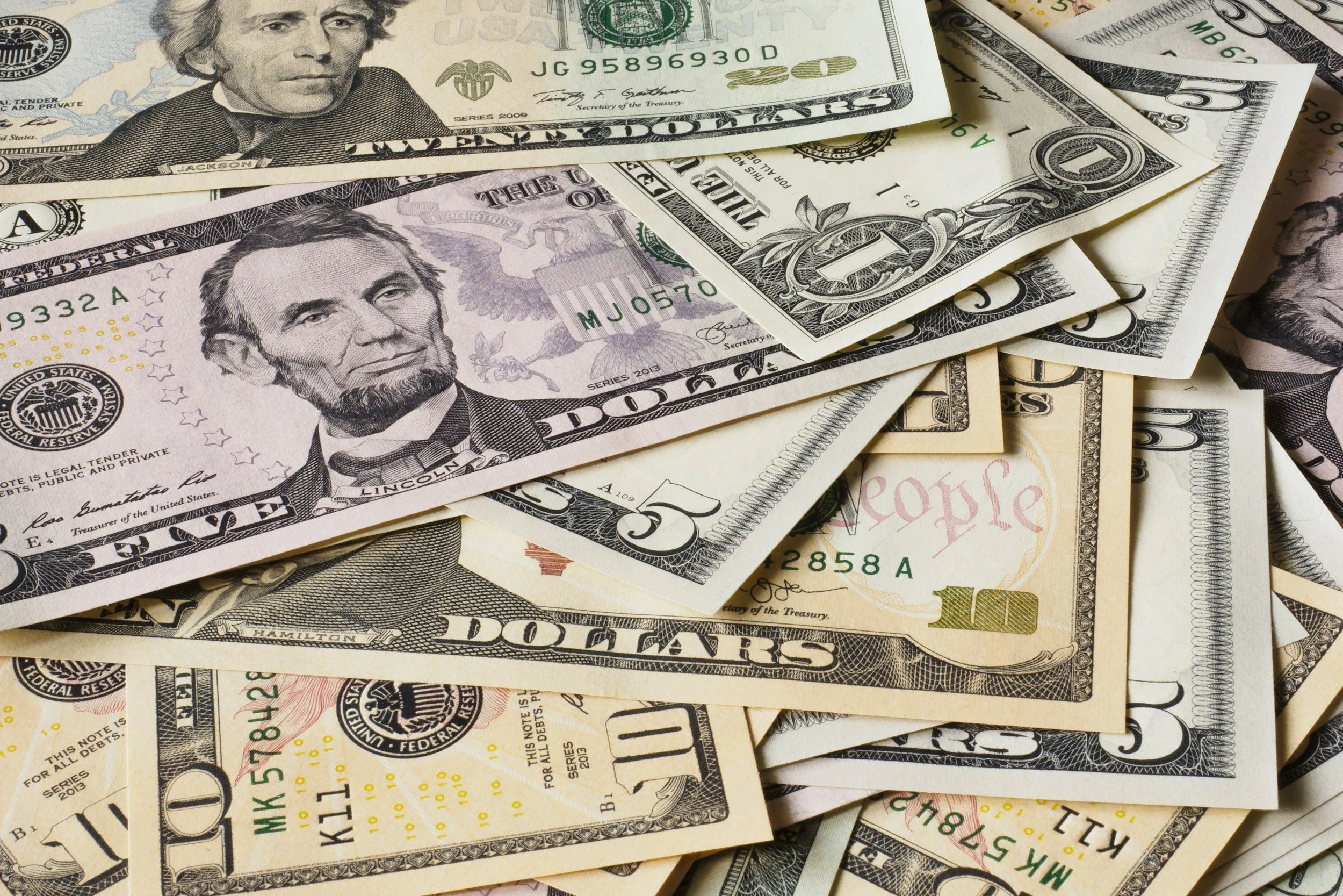 Multiple U.S. dollar bills, including twenty-dollar and ten-dollar notes, with portraits of Andrew Jackson and Alexander Hamilton.