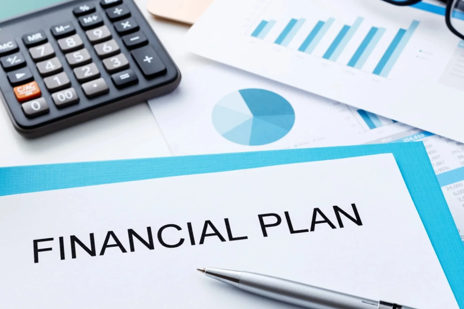 A document titled financial plan on top of various graphs and charts next to a calculator.