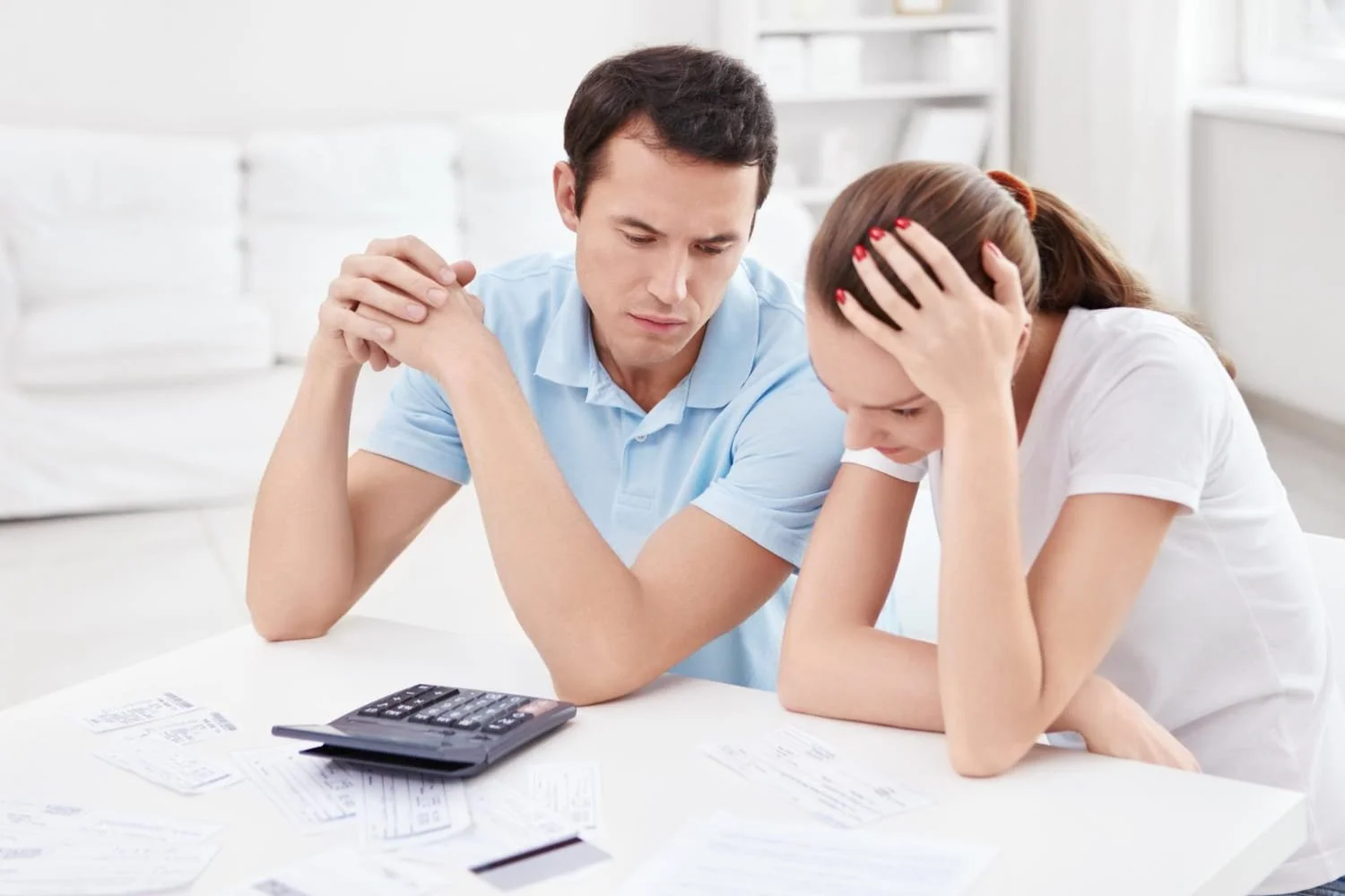 A worried couple reviewing various financial documents and reports.