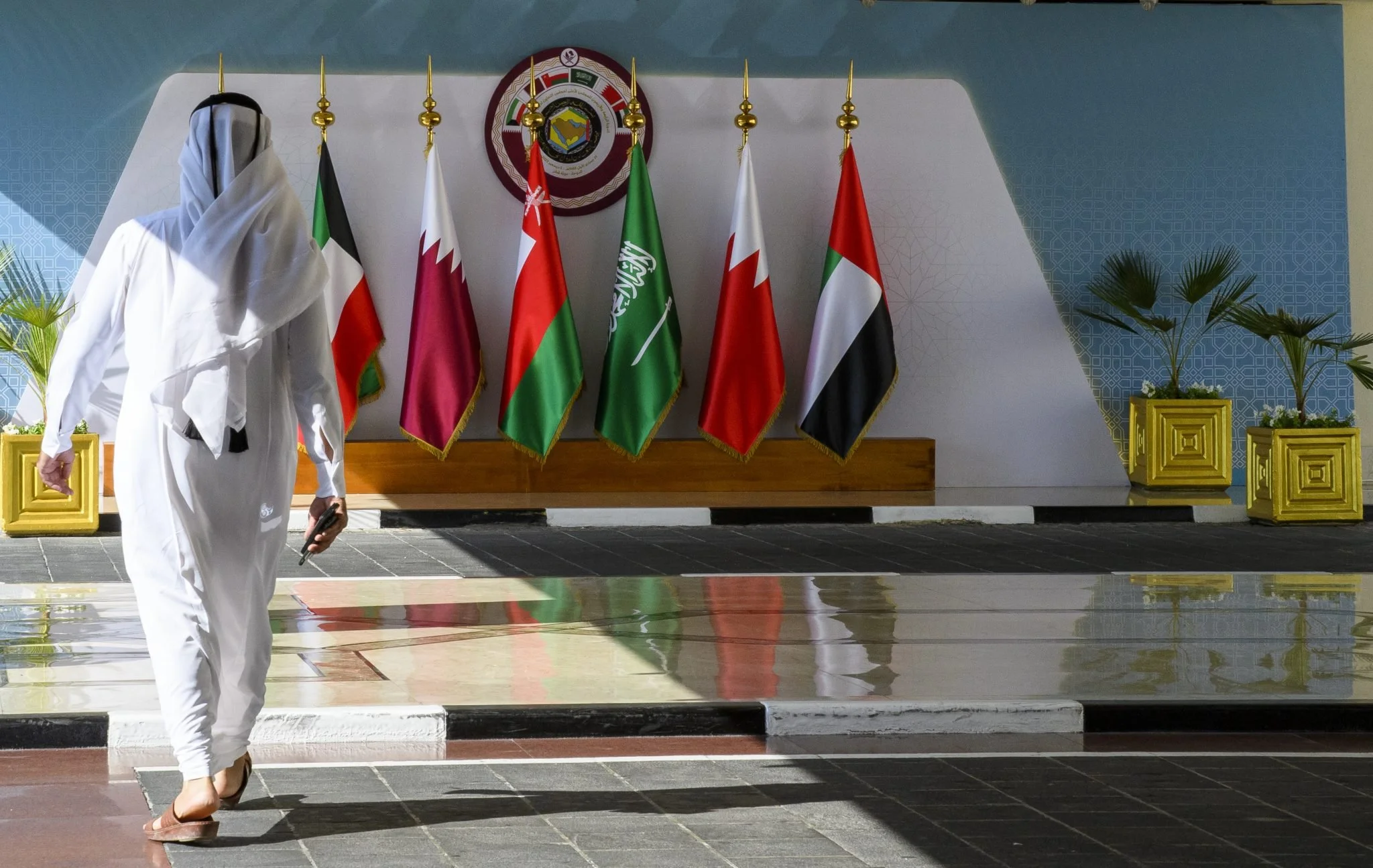 A Qatari man is walking past the flags of the Gulf Cooperation Council at the Sheraton Hotel in Doha, Qatar, on December 3, 2023, two days prior to the start of the GCC leaders' summit. (Photo by Noushad Thekkayil/NurPhoto via AP)