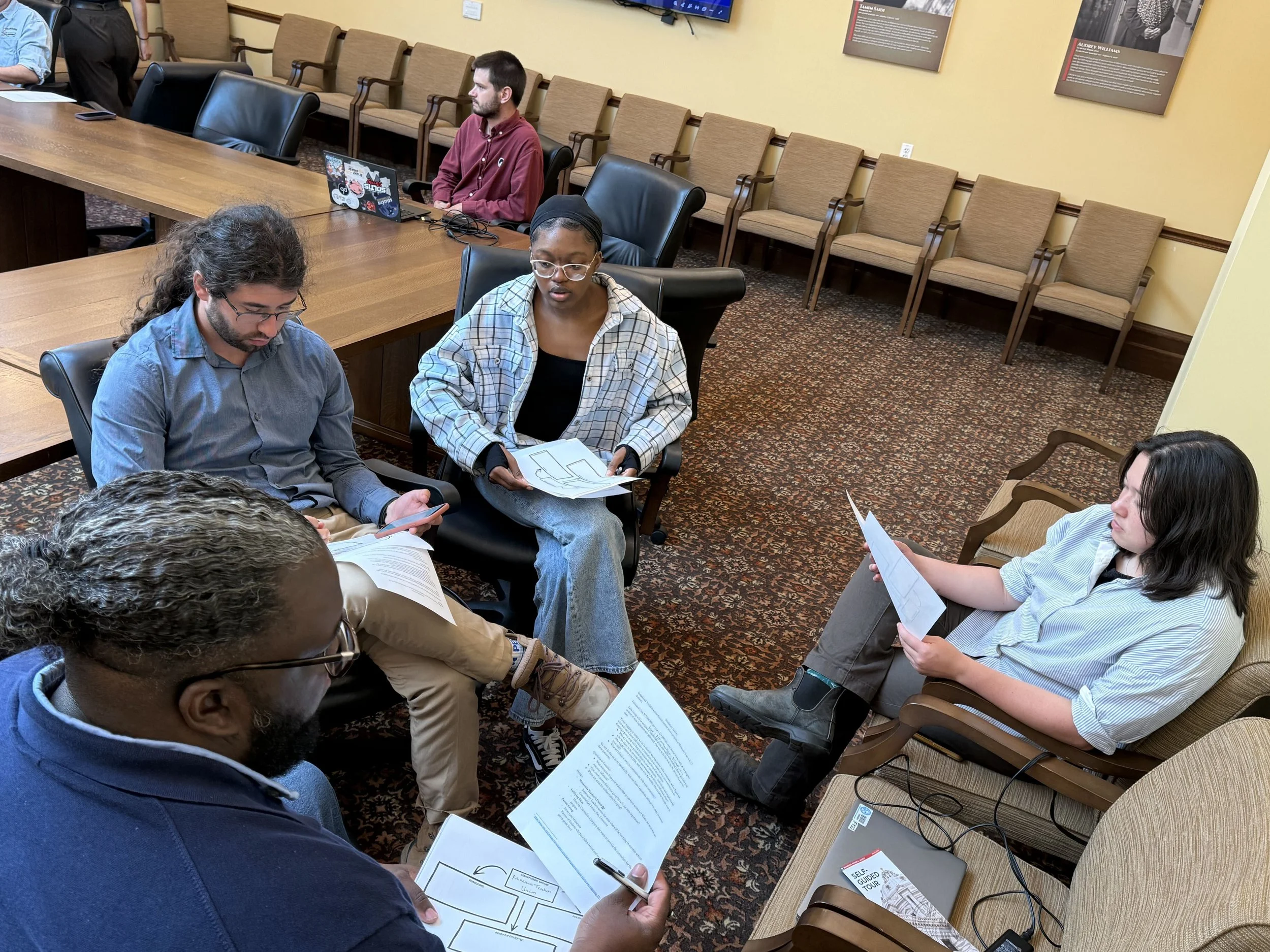 A group of four Fellows sits in a circle, participating in the power mapping simulation.