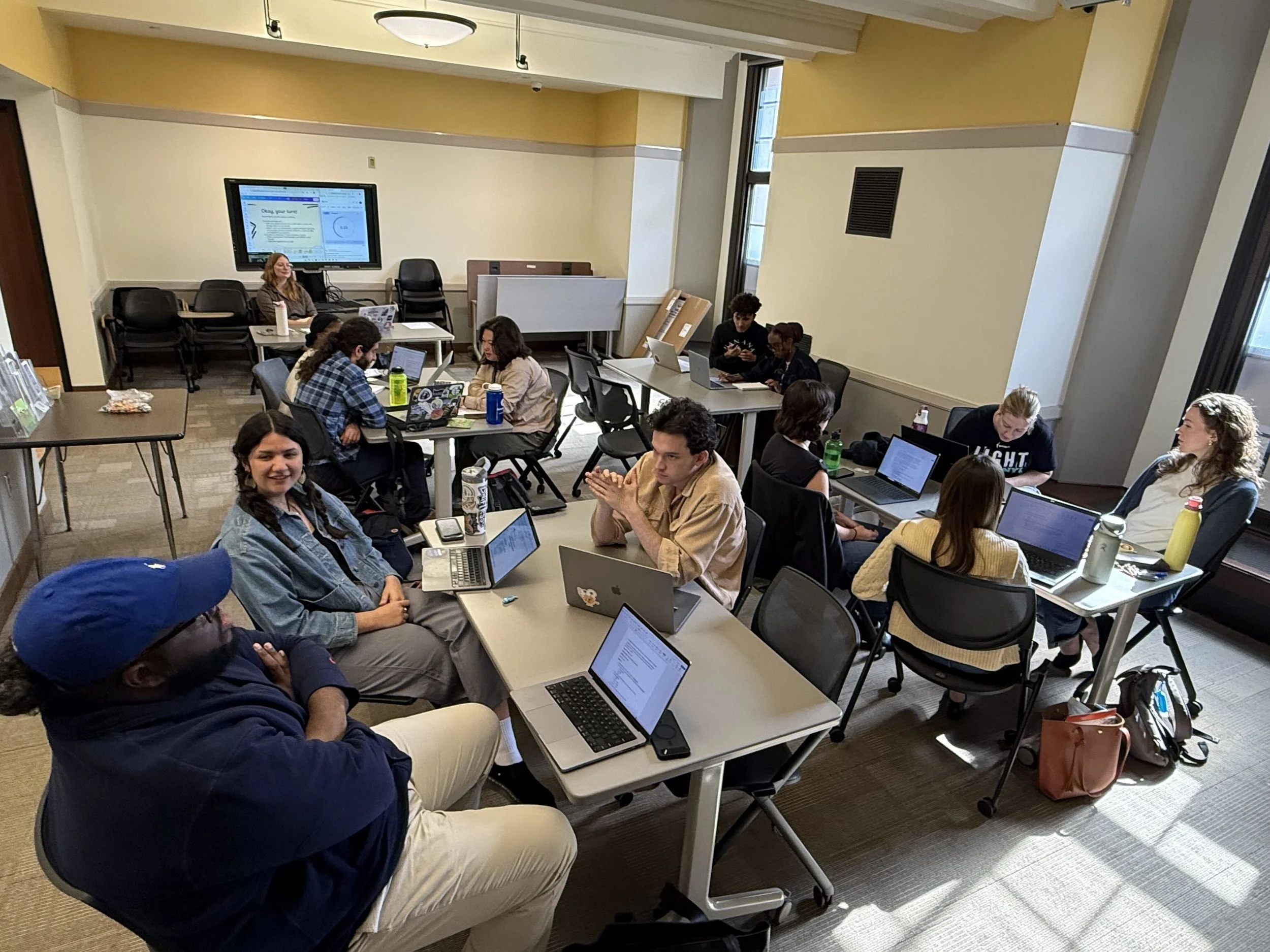 The fellows sit in the workshop room and discuss survey design for their host sites.
