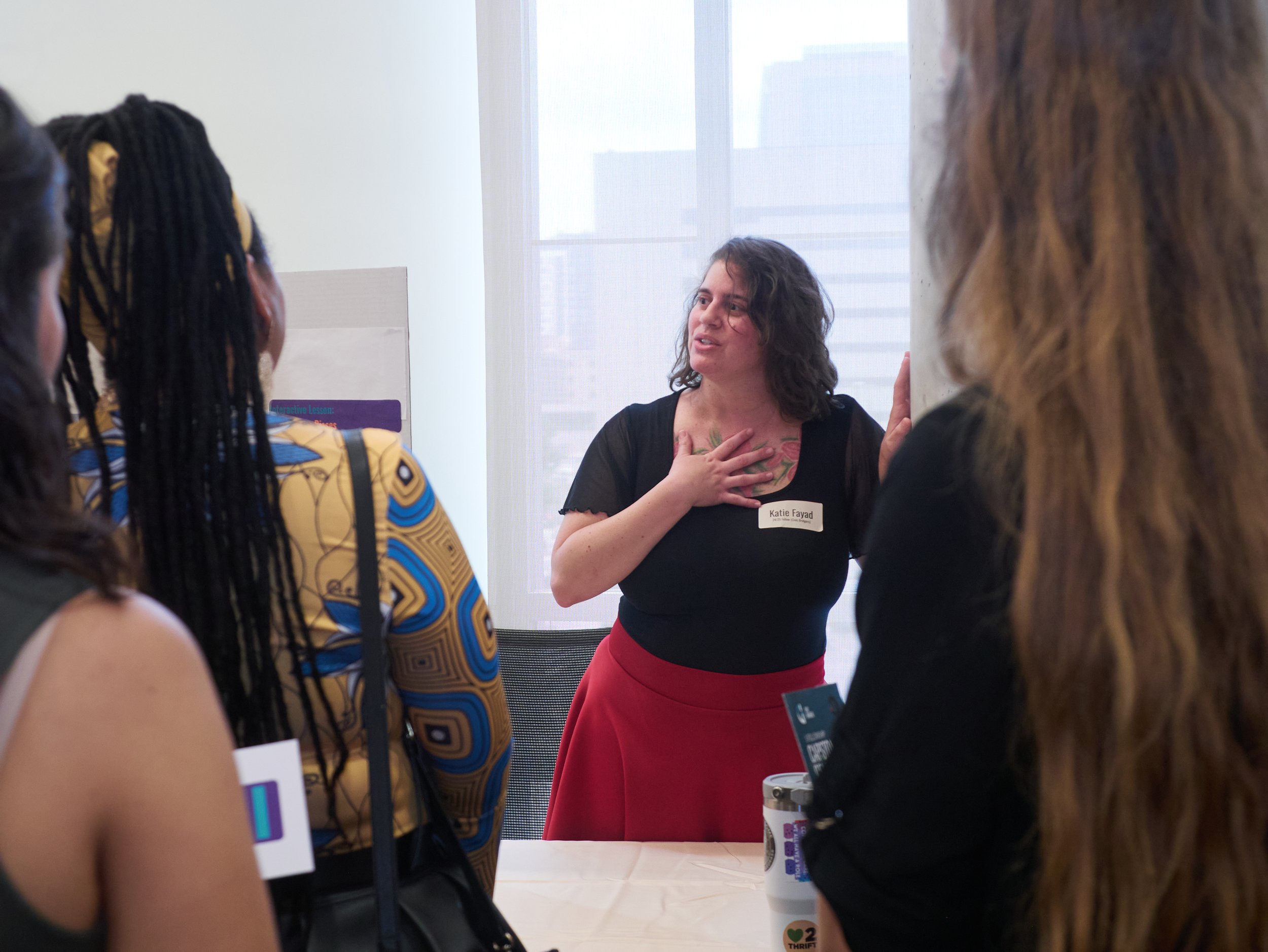 Young woman in red skirt presenting to a group.