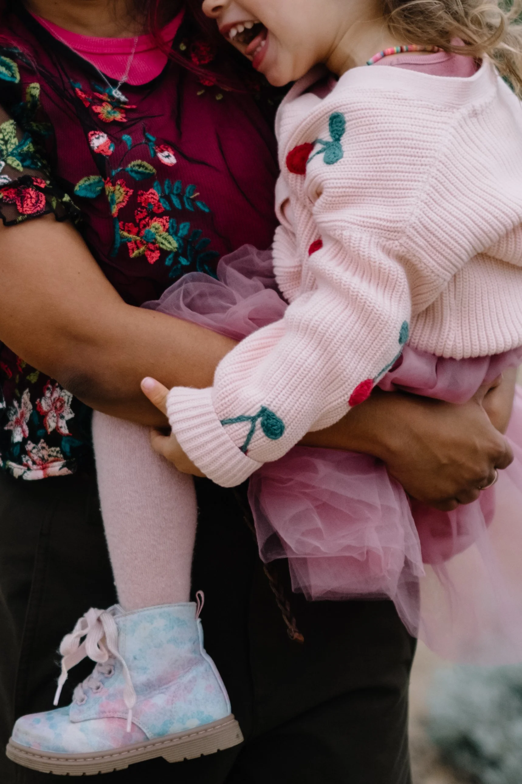 Close-up of a woman holding a smiling young girl in her arms, showing their joyful interaction.