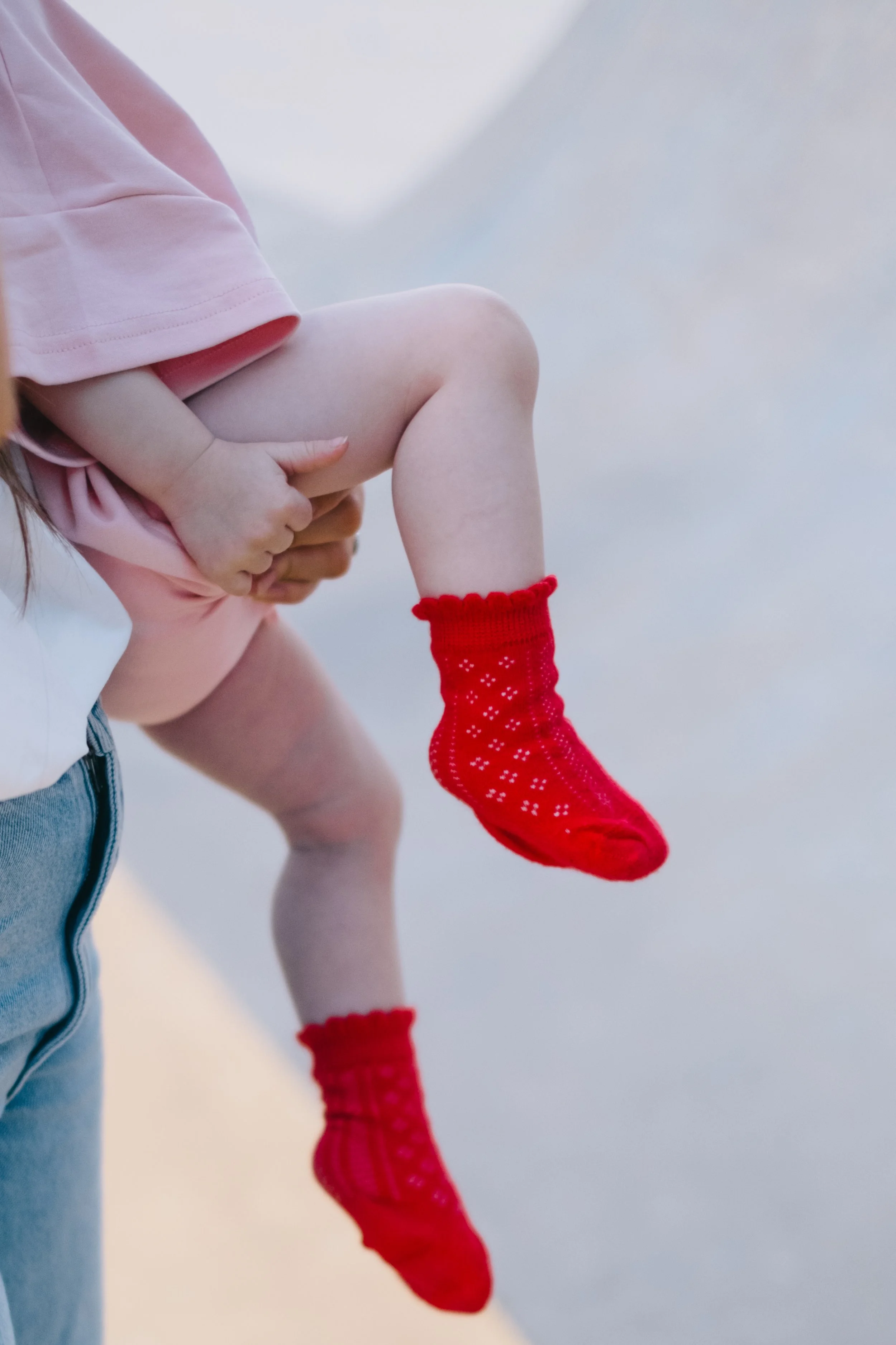 Child wearing red Christmas stockings being carried by an adult.
